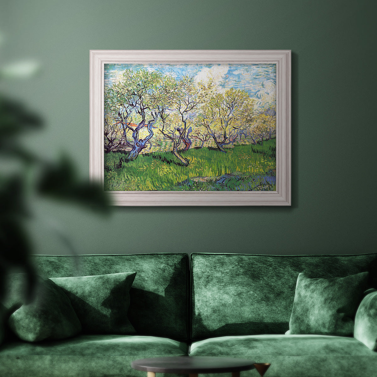 Impressionist spring orchard landscape by Vincent van Gogh in an ornate weathered white frame displayed in a dark-toned interior setting.