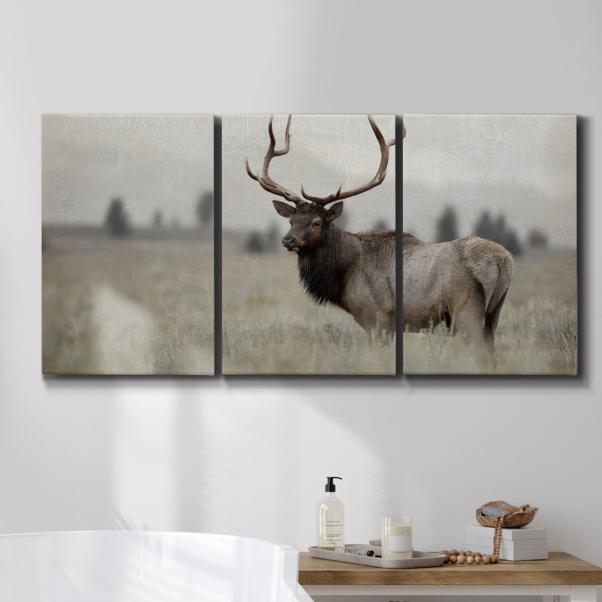Three-panel canvas wall art featuring elk standing in open grassland, displayed in a bathroom above a bathtub.