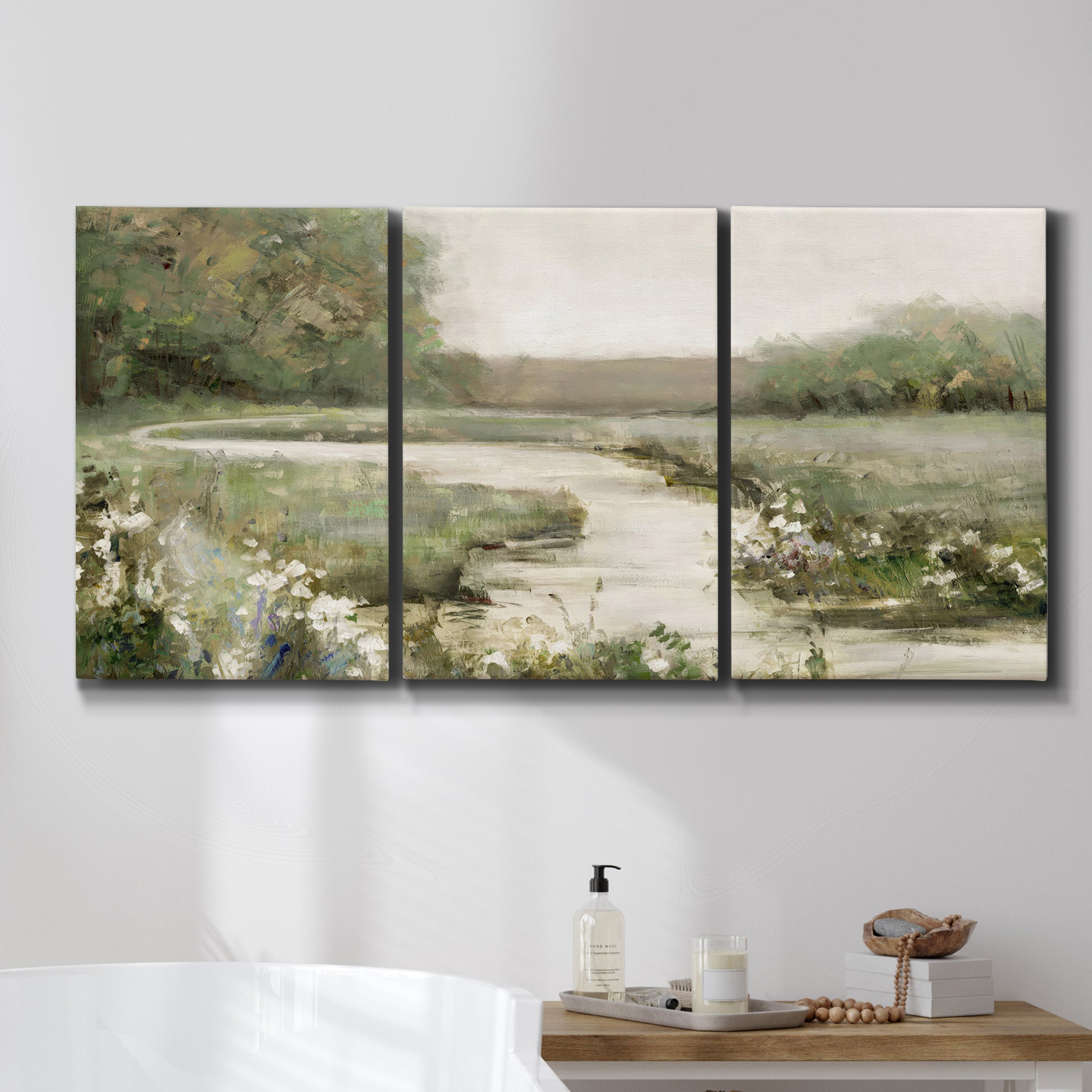 Three-panel canvas wall art featuring narrow path through quiet landscape, displayed in a bathroom above a bathtub.