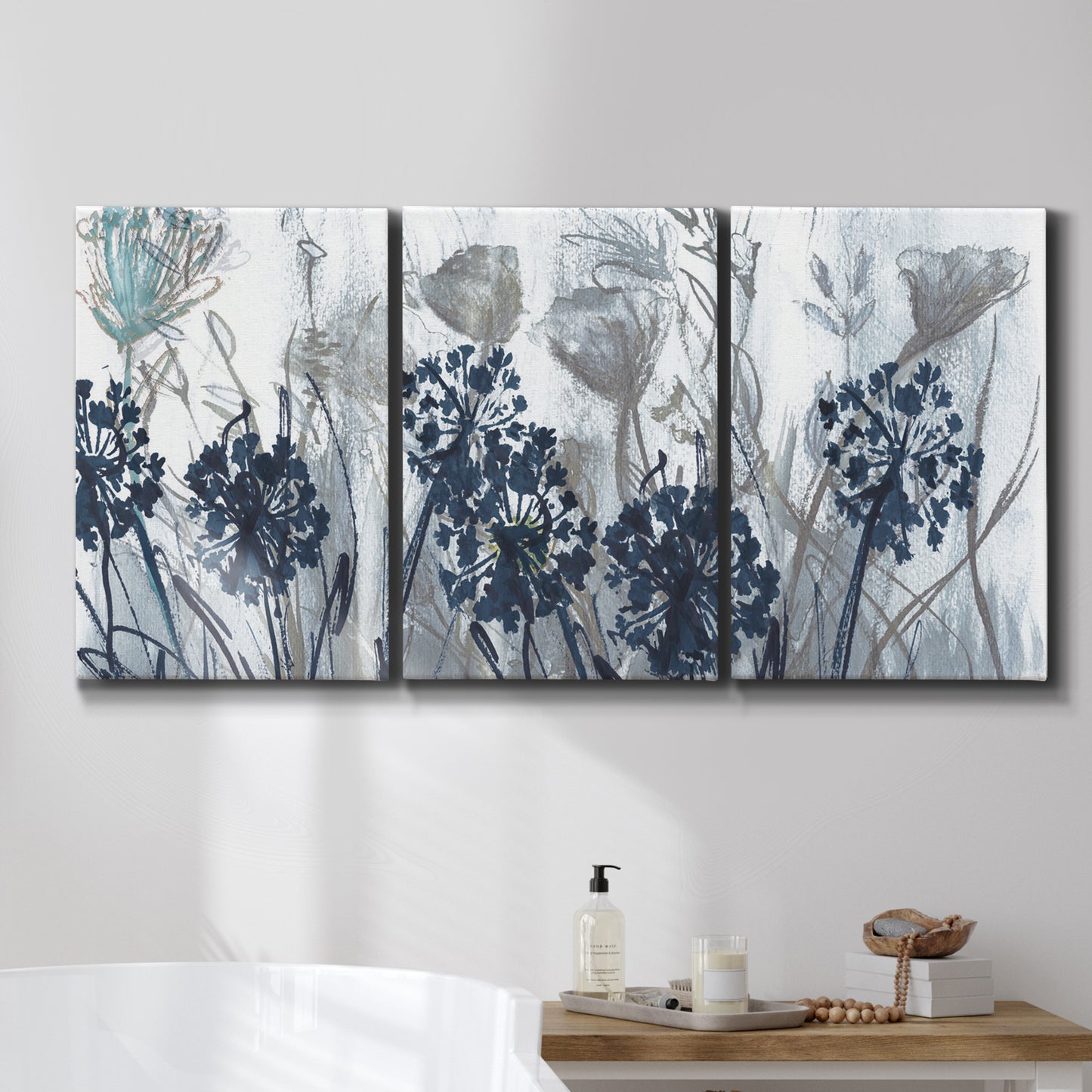 Three-panel canvas wall art featuring indigo floral abstraction, displayed in a bathroom above a bathtub.