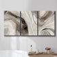 Three-panel canvas wall art featuring layered stone inspired abstract forms, displayed in a bathroom above a bathtub.