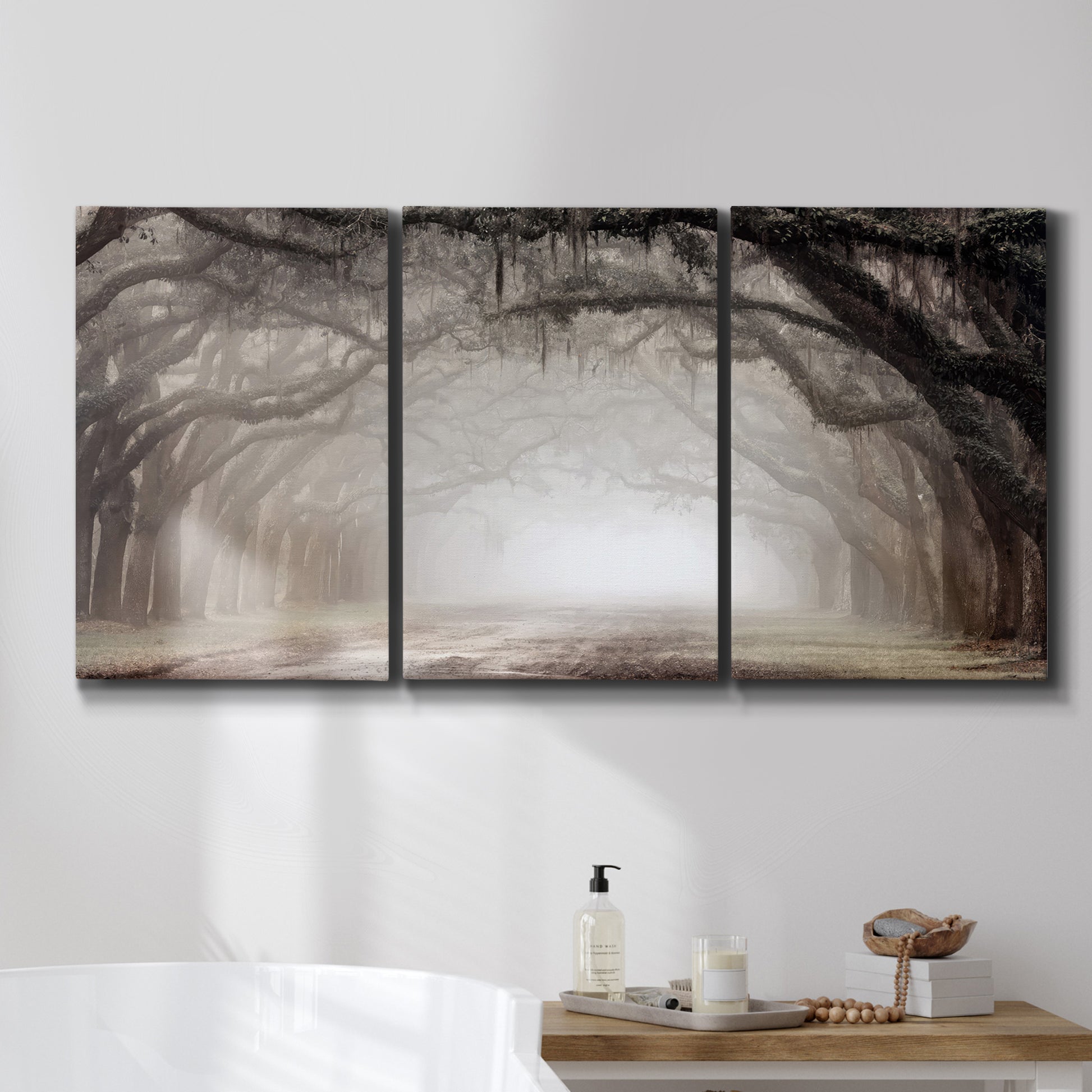 Three-panel canvas wall art featuring tree lined plantation road, displayed in a bathroom above a bathtub.