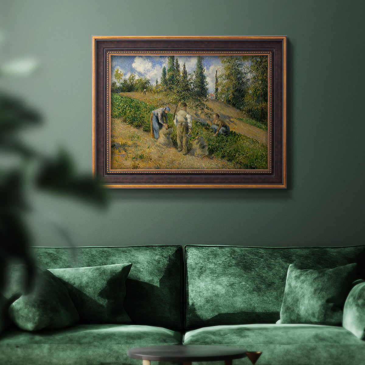 Impressionist countryside harvest scene by Camille Pissarro in an ornate bronzed mahogany wood frame displayed in a dark-toned interior setting.