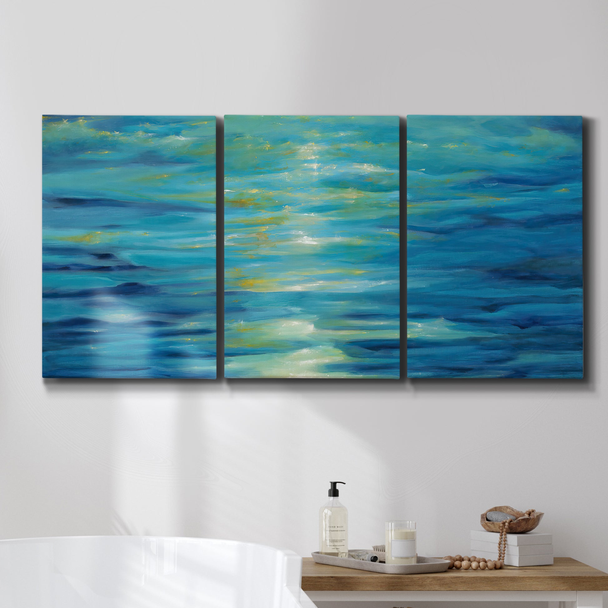 Three-panel canvas wall art featuring deep blue ocean water abstraction, displayed in a bathroom above a bathtub.