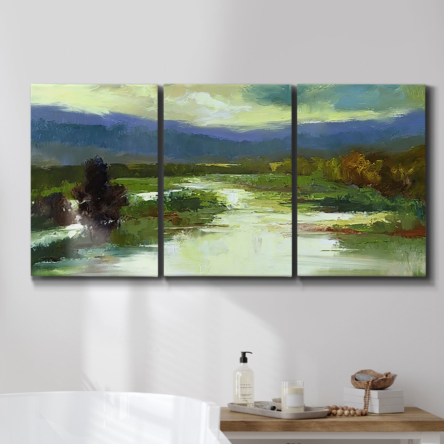 Three-panel canvas wall art featuring open meadow landscape with distant hills, displayed in a bathroom above a bathtub.