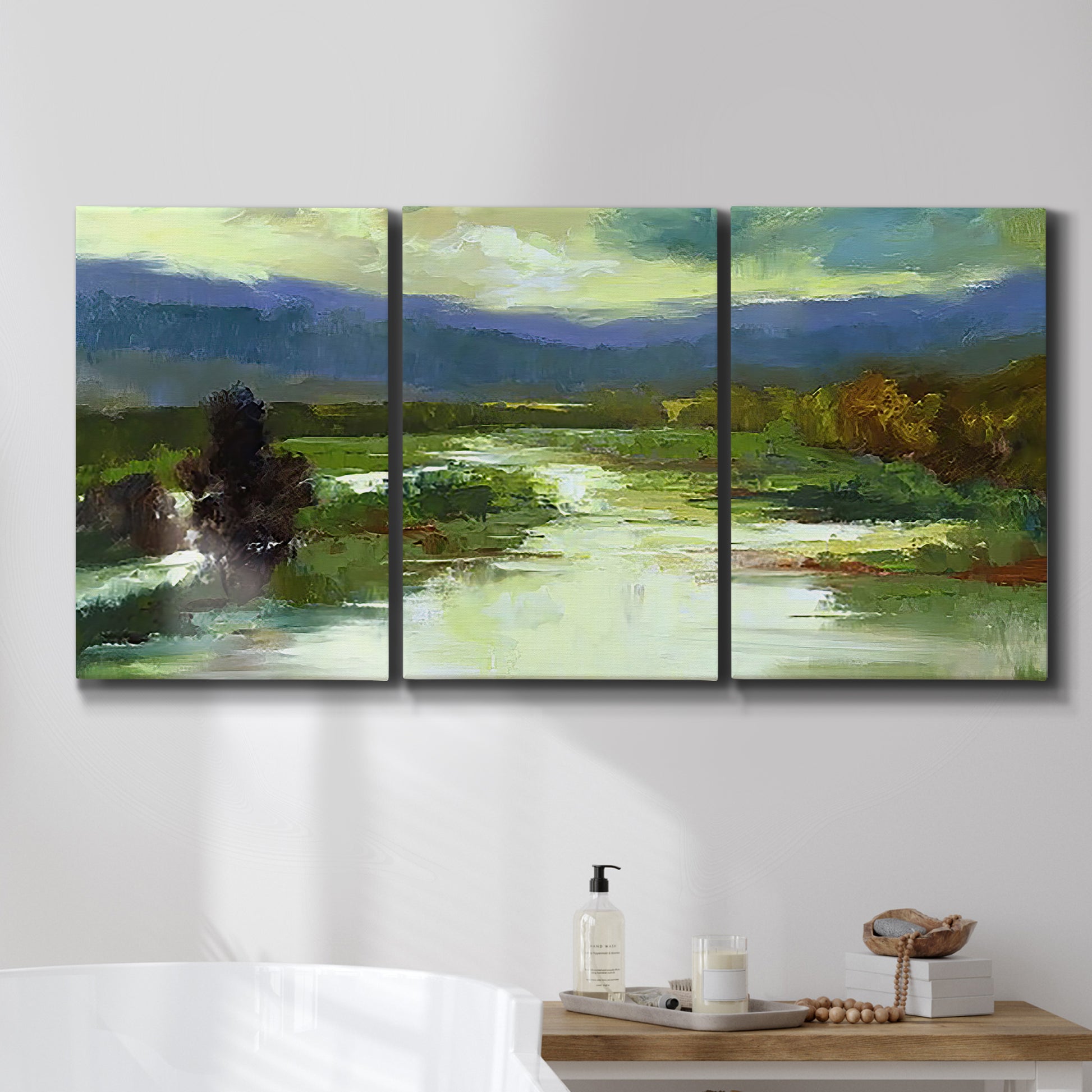 Three-panel canvas wall art featuring open meadow landscape with distant hills, displayed in a bathroom above a bathtub.