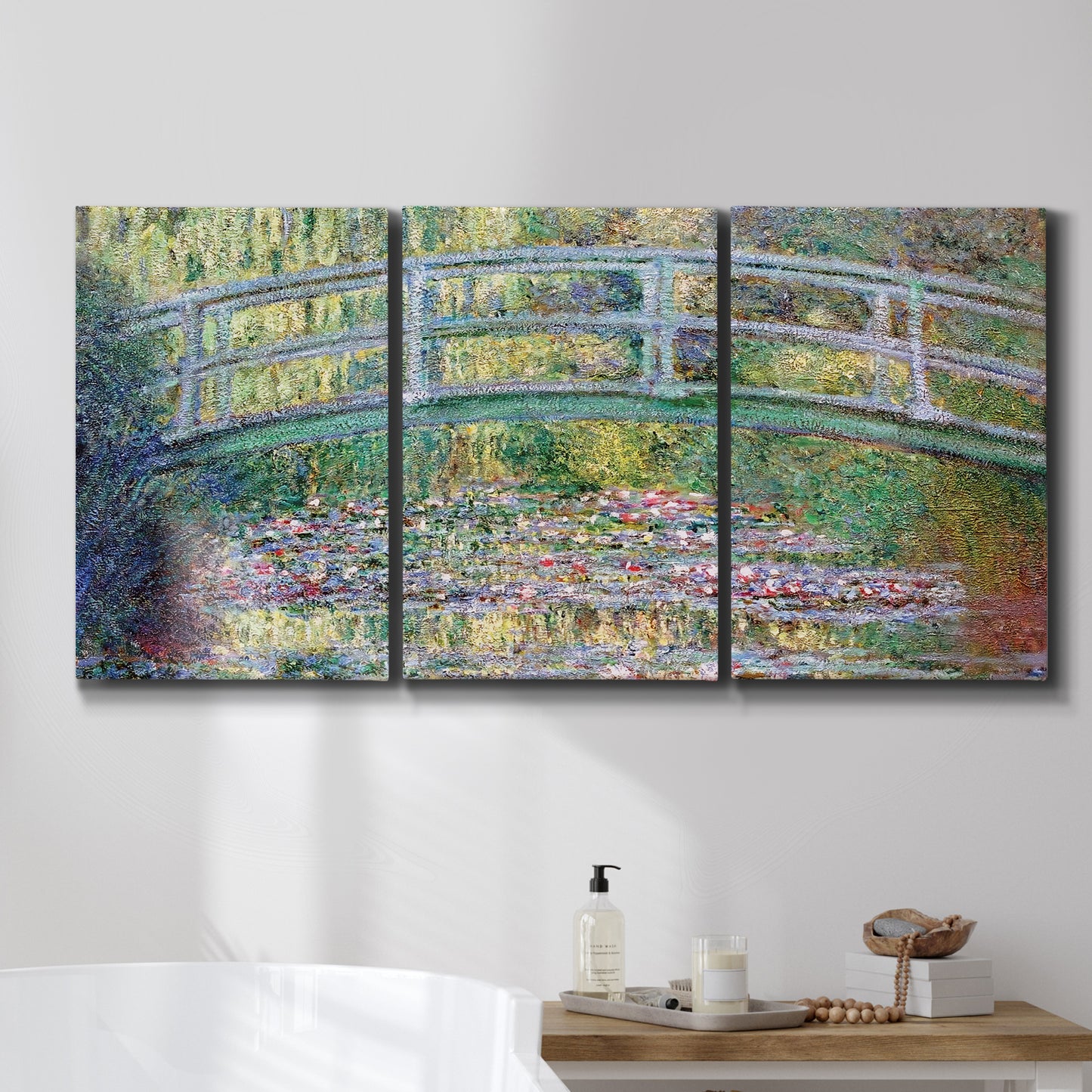 Three-panel canvas wall art featuring water lilies with arched bridge, displayed in a bathroom above a bathtub.