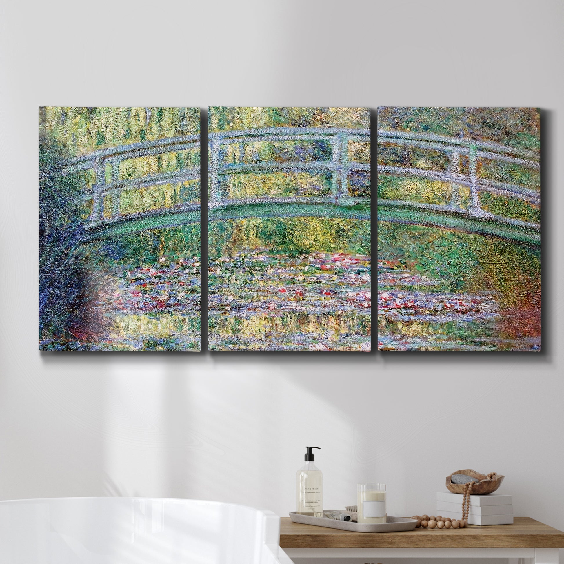 Three-panel canvas wall art featuring water lilies with arched bridge, displayed in a bathroom above a bathtub.
