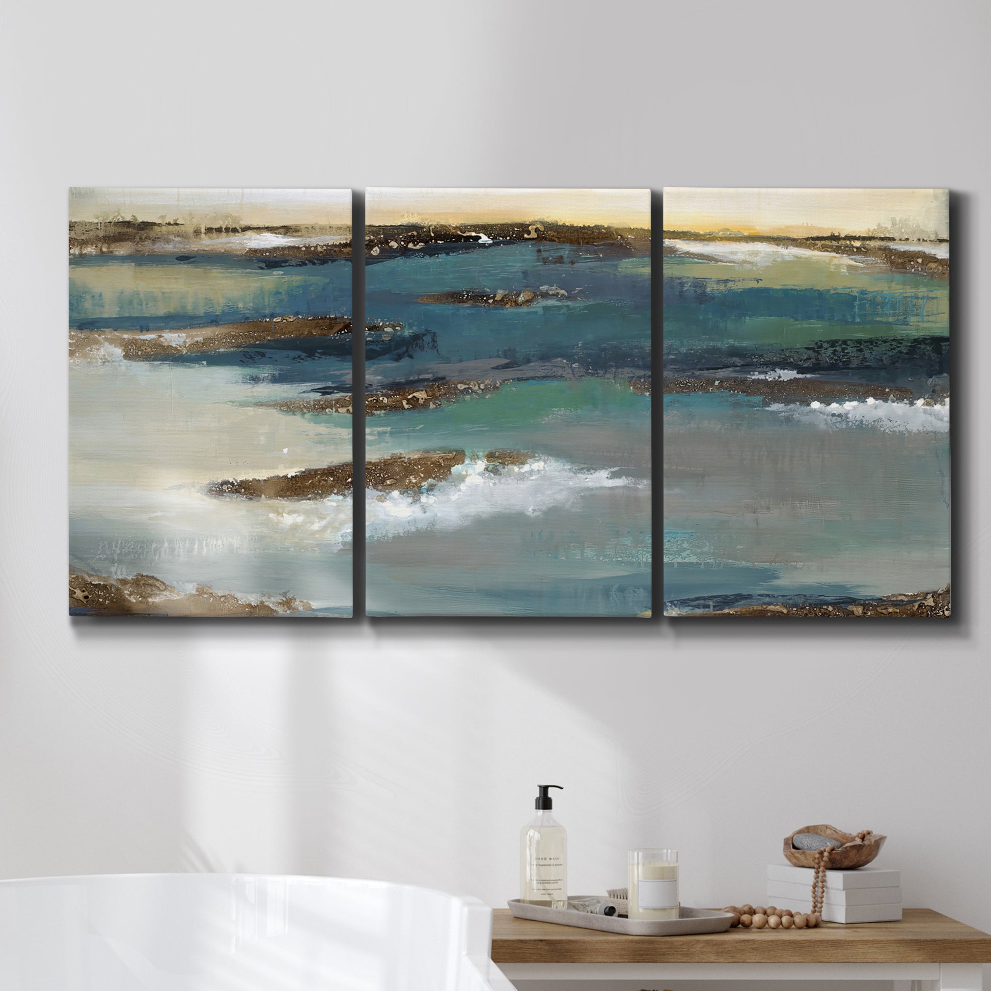Three-panel canvas wall art featuring rocky coastal bluff above sea, displayed in a bathroom above a bathtub.