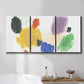 Three-panel canvas wall art featuring inkblot style abstract color symmetry, displayed in a bathroom above a bathtub.