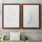 Set of two maple barnwood framed canvas prints depicting a coordinated art pair of single continuous-line leafy branches rendered as minimalist botanical line drawings above a sofa in a modern living room.