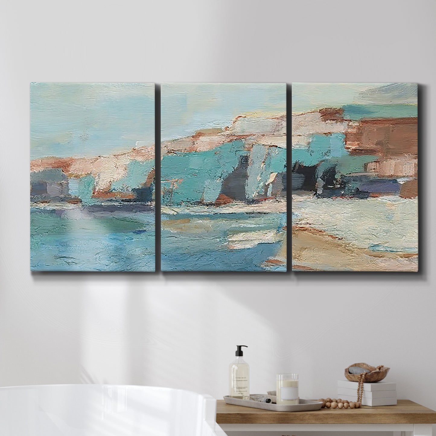 Three-panel canvas wall art featuring coastal shoreline with soft waves, displayed in a bathroom above a bathtub.