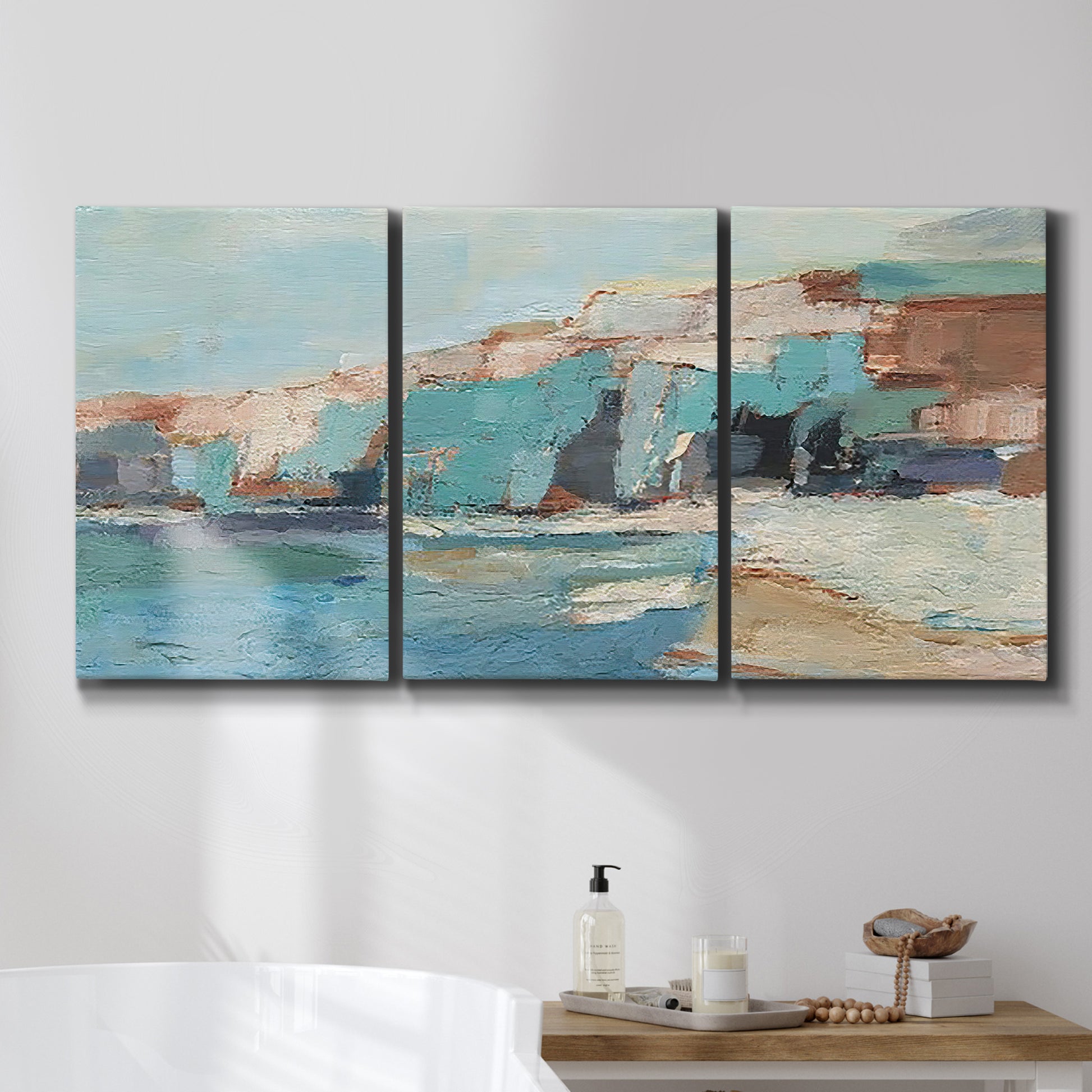 Three-panel canvas wall art featuring coastal shoreline with soft waves, displayed in a bathroom above a bathtub.