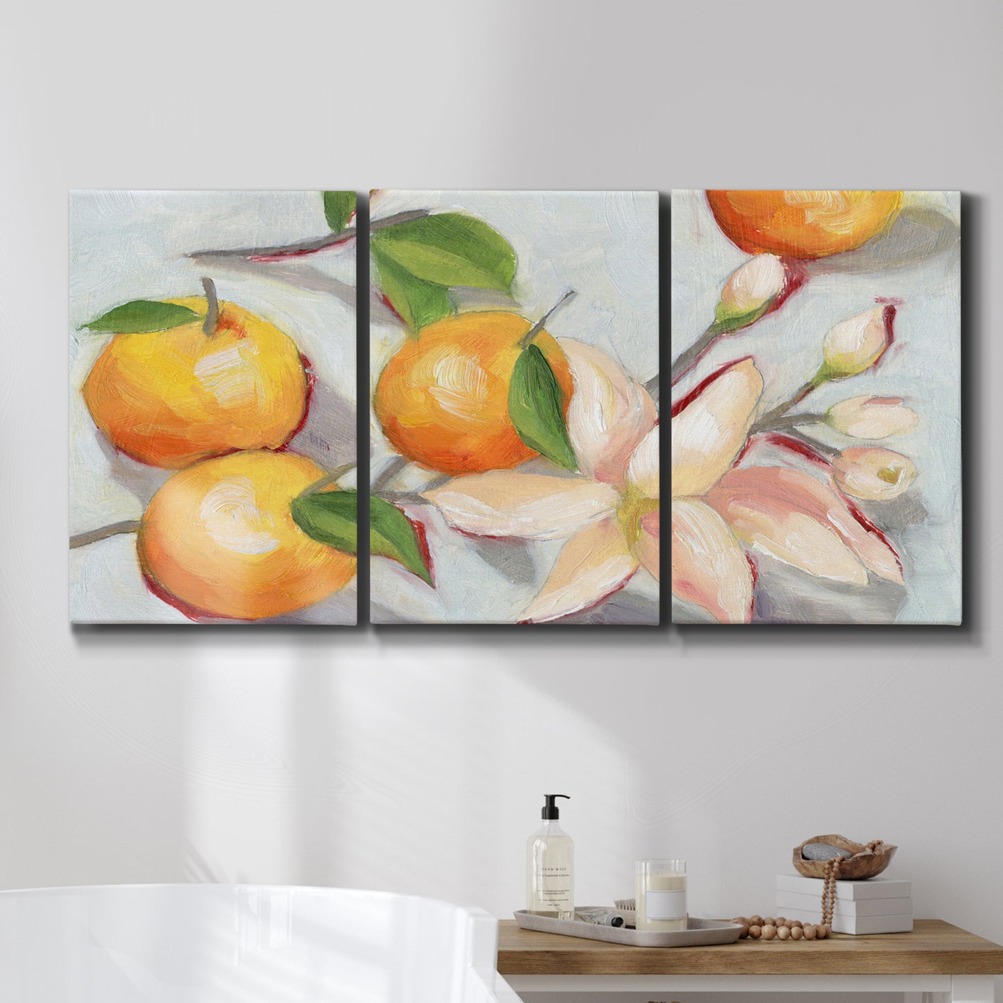 Three-panel canvas wall art featuring bright tangerine still life blossoms, displayed in a bathroom above a bathtub.