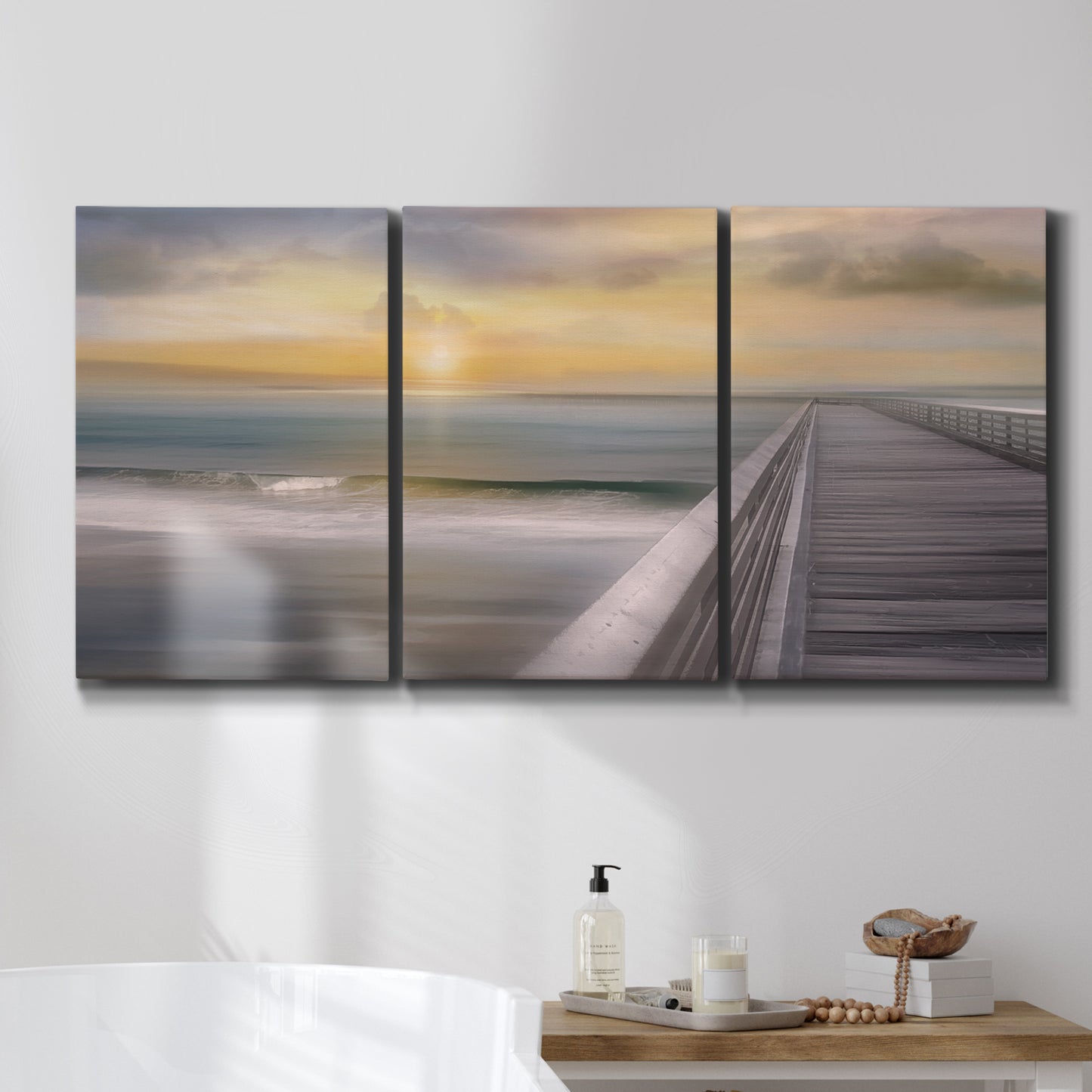 Three-panel canvas wall art featuring tropical beach at sunset photograph, displayed in a bathroom above a bathtub.