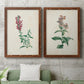 Set of two maple barnwood framed canvas prints depicting antique floral illustrations featuring a tall red bloom and a clustered mauve flower above a sofa in a modern living room.
