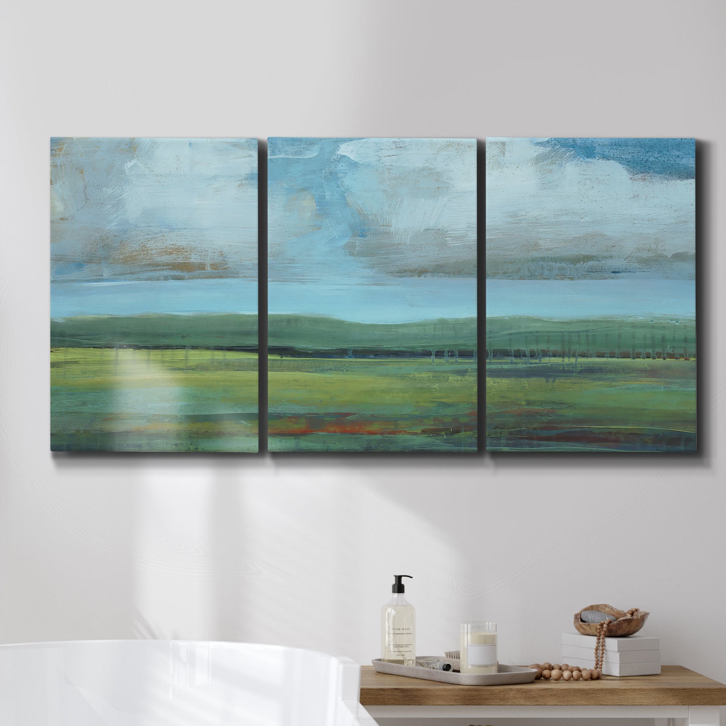Three-panel canvas wall art featuring wide valley landscape with rolling hills, displayed in a bathroom above a bathtub.