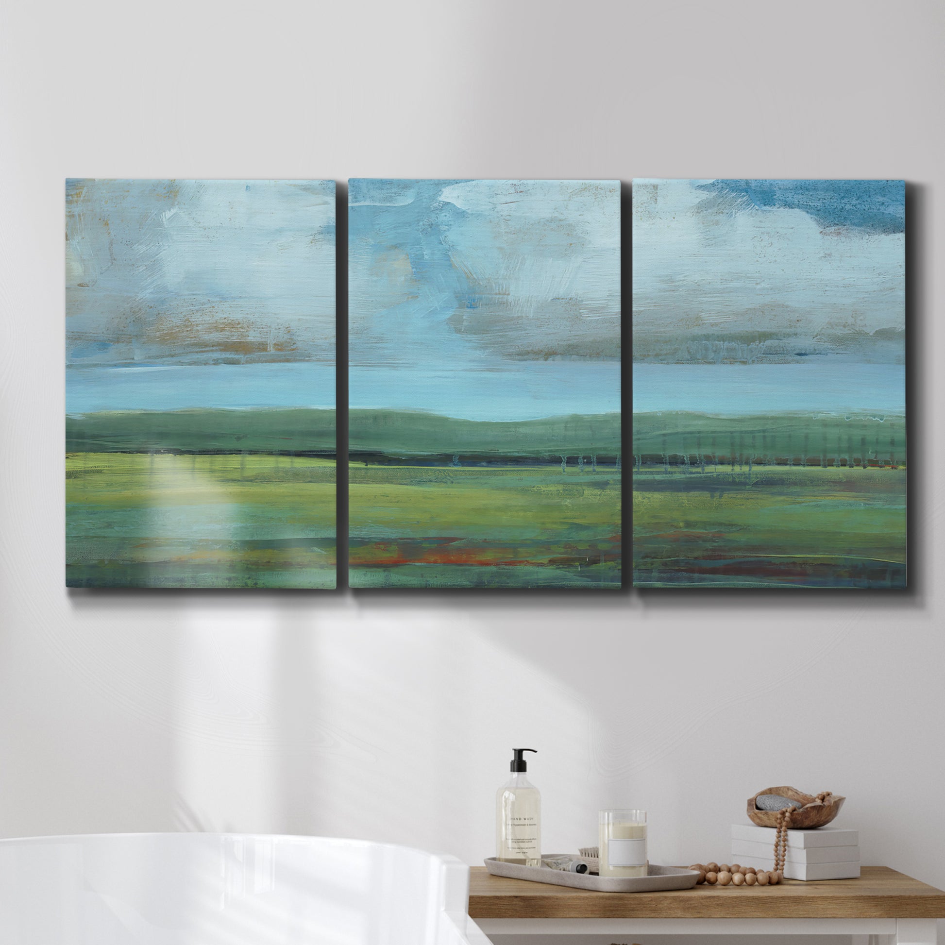 Three-panel canvas wall art featuring wide valley landscape with rolling hills, displayed in a bathroom above a bathtub.