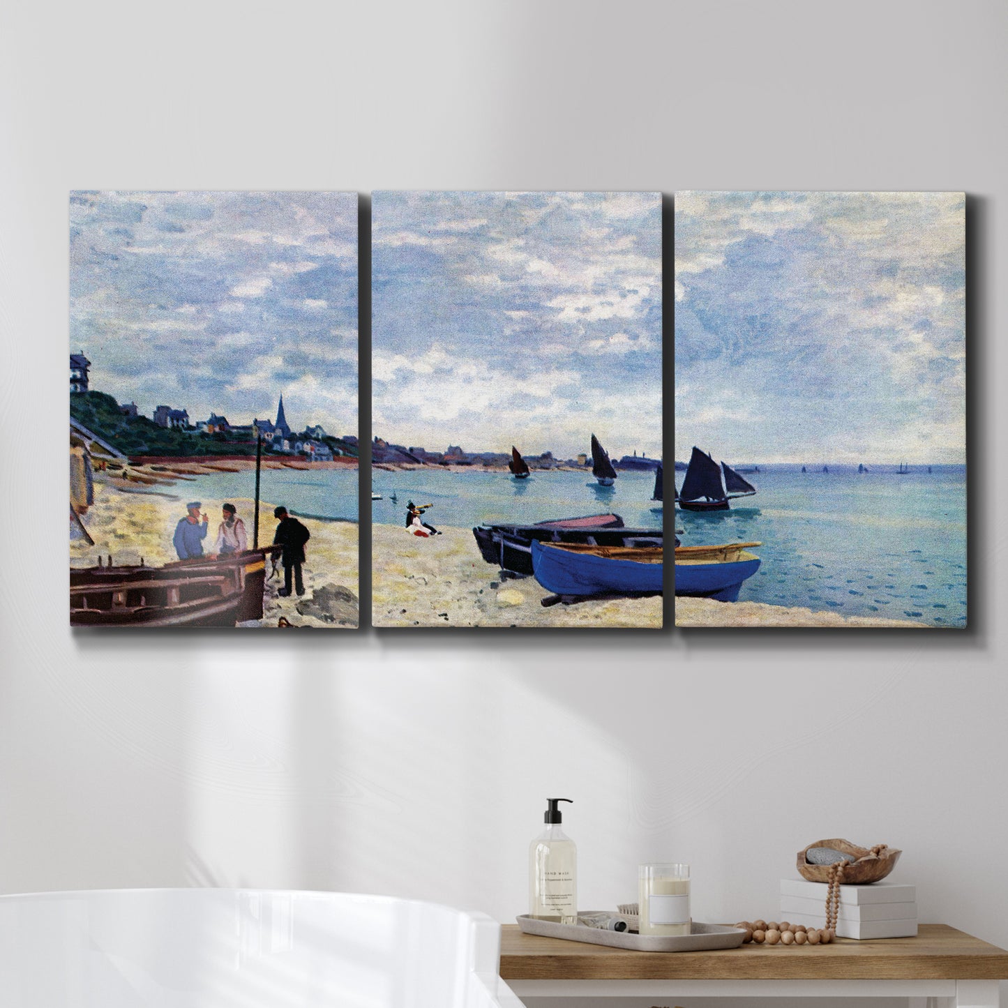 Three-panel canvas wall art featuring busy beach scene with shoreline, displayed in a bathroom above a bathtub.
