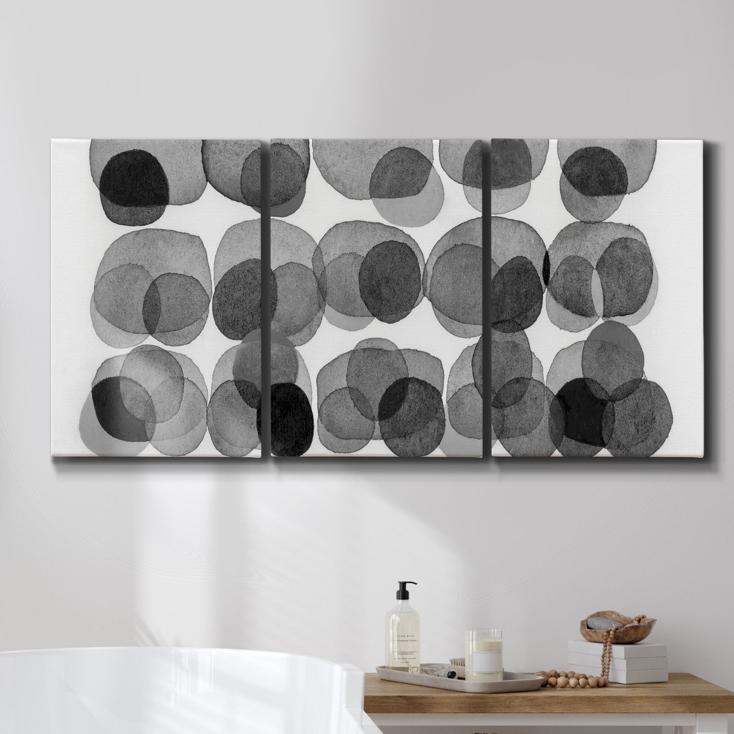 Three-panel canvas wall art featuring geometric abstract watercolor forms, displayed in a bathroom above a bathtub.