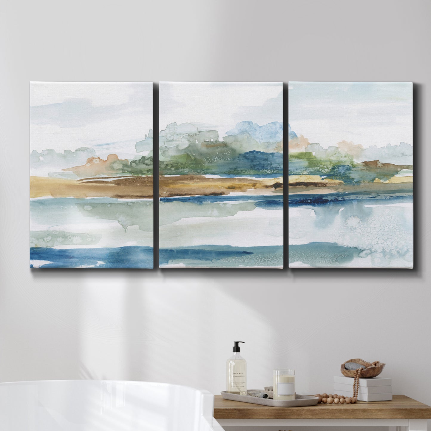 Three-panel canvas wall art featuring flowing blue abstract watercolor, displayed in a bathroom above a bathtub.