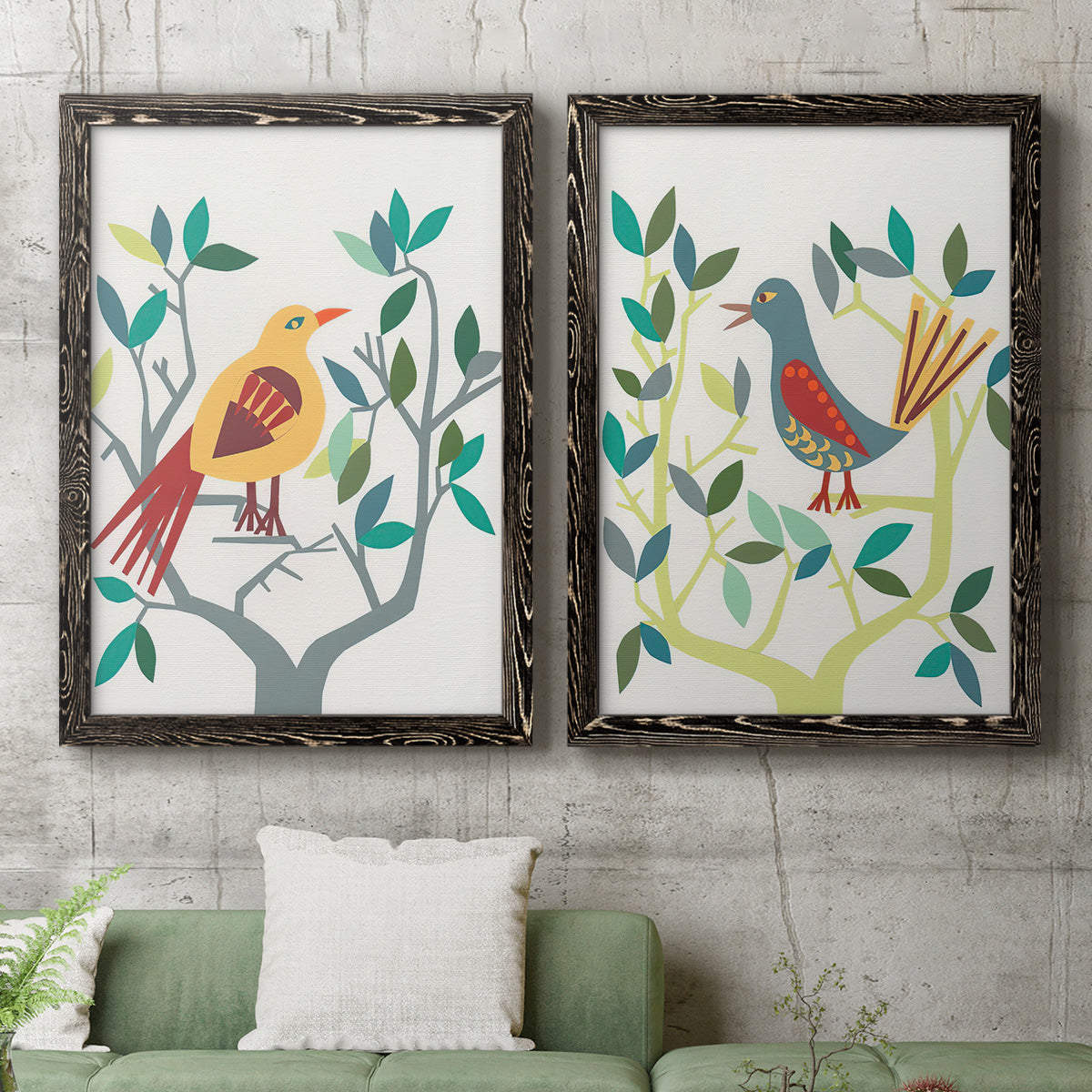 Set of two black barnwood framed canvas prints depicting a coordinated art pair of stylized colorful birds perched among leafy branches rendered as modern folk-art bird illustrations above a sofa in a modern living room.
