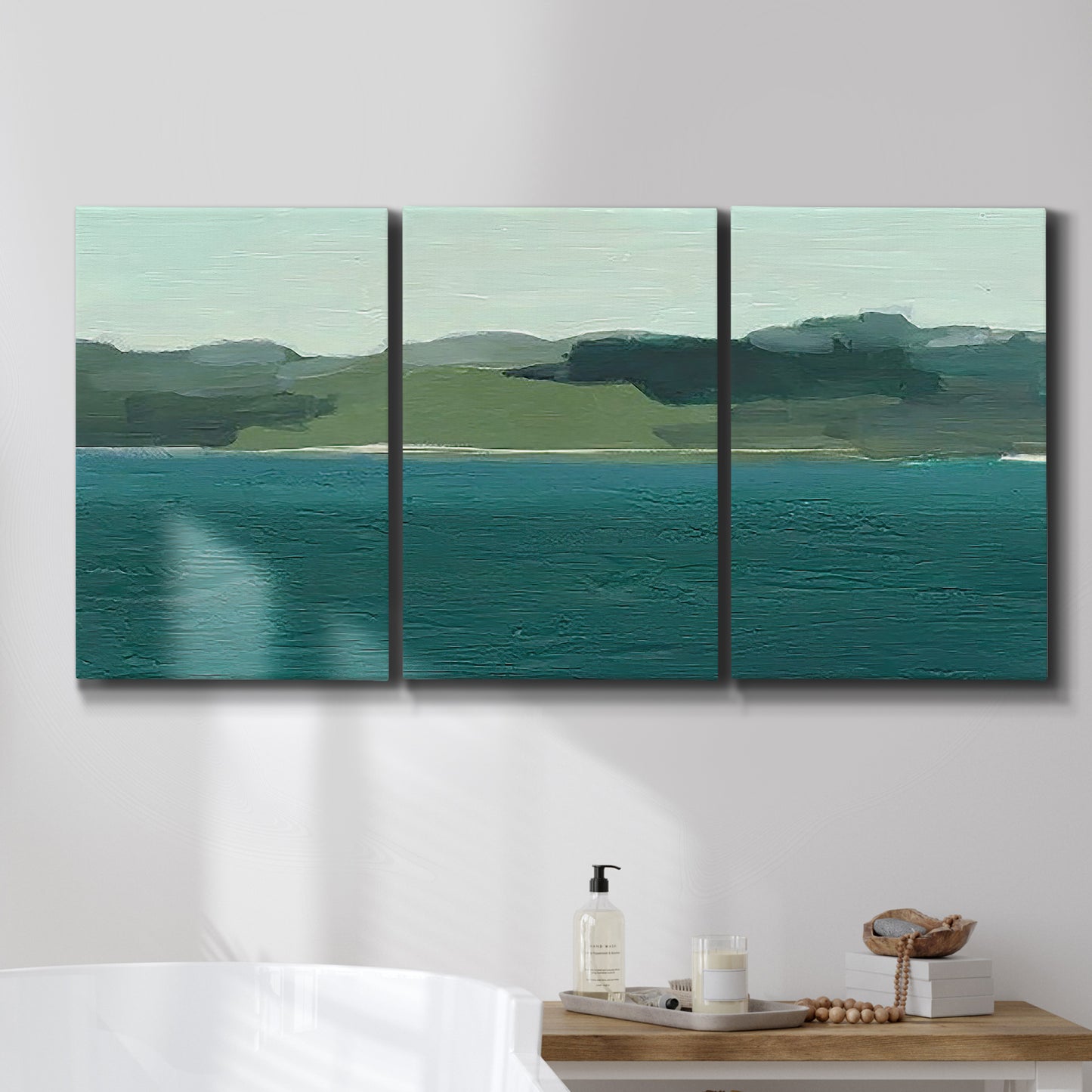Three-panel canvas wall art featuring calm lake water under open sky, displayed in a bathroom above a bathtub.