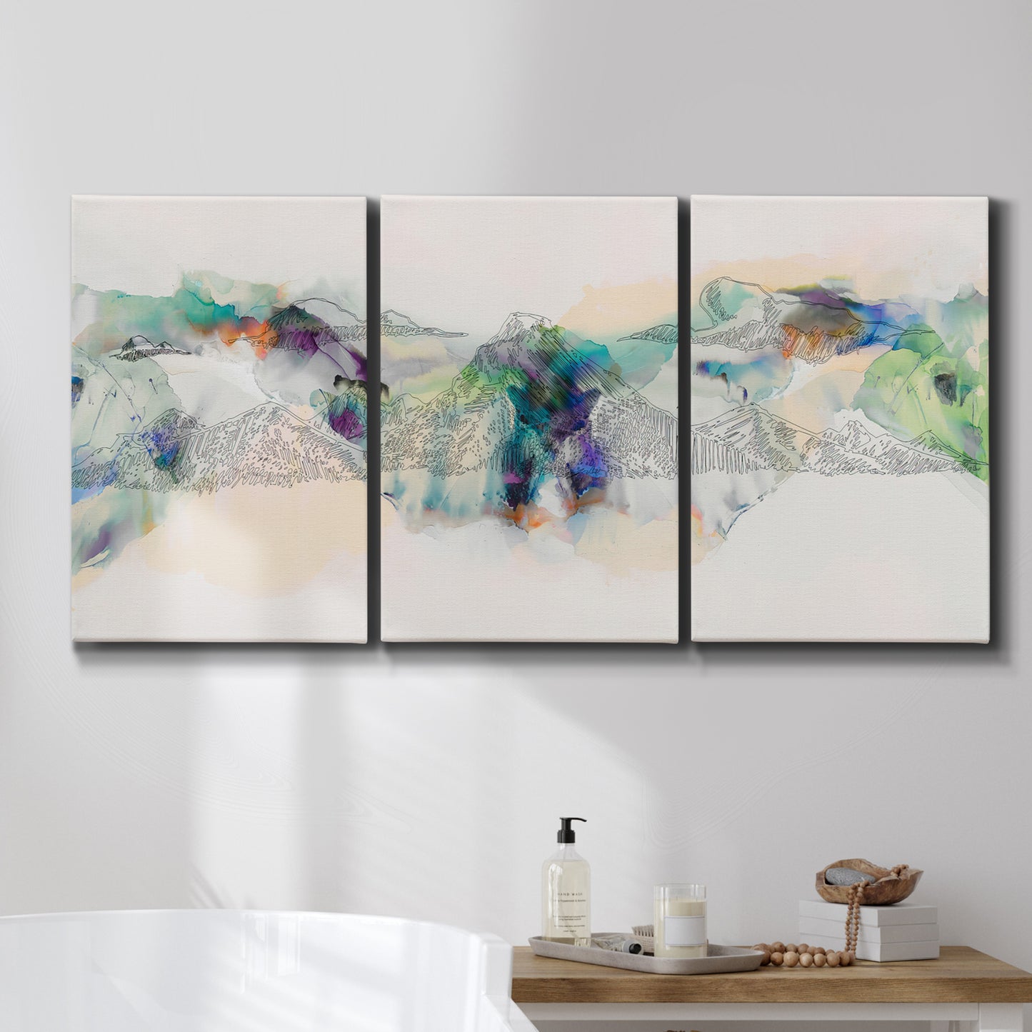 Three-panel canvas wall art featuring abstract mountain range watercolor, displayed in a bathroom above a bathtub.