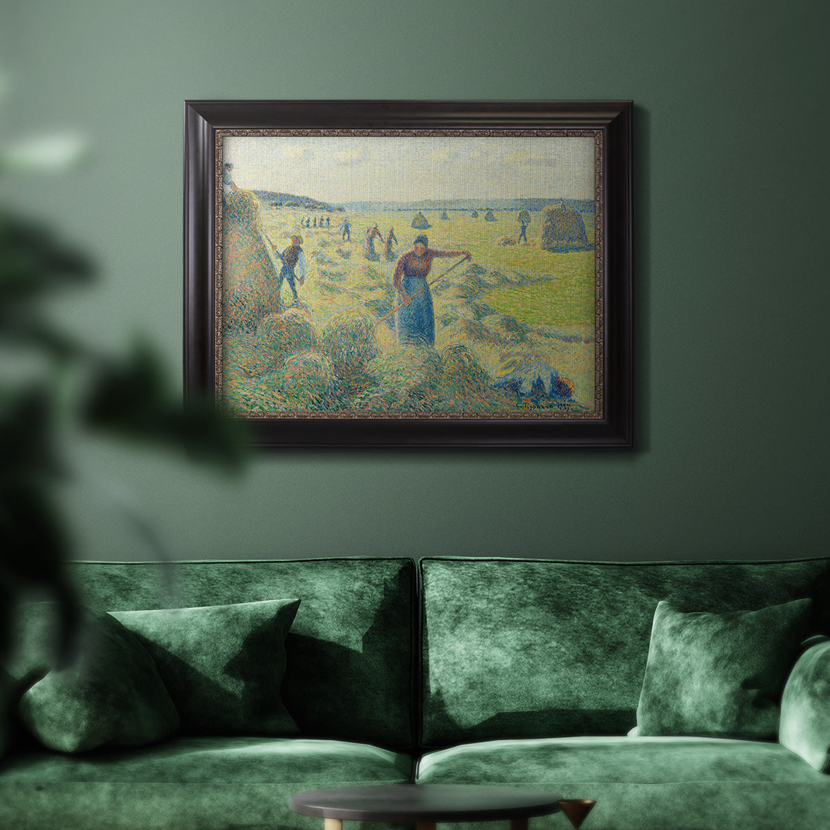 Impressionist rural hay harvest landscape by Camille Pissarro in an ornate black frame with gilded inner detail displayed in a dark-toned interior setting.