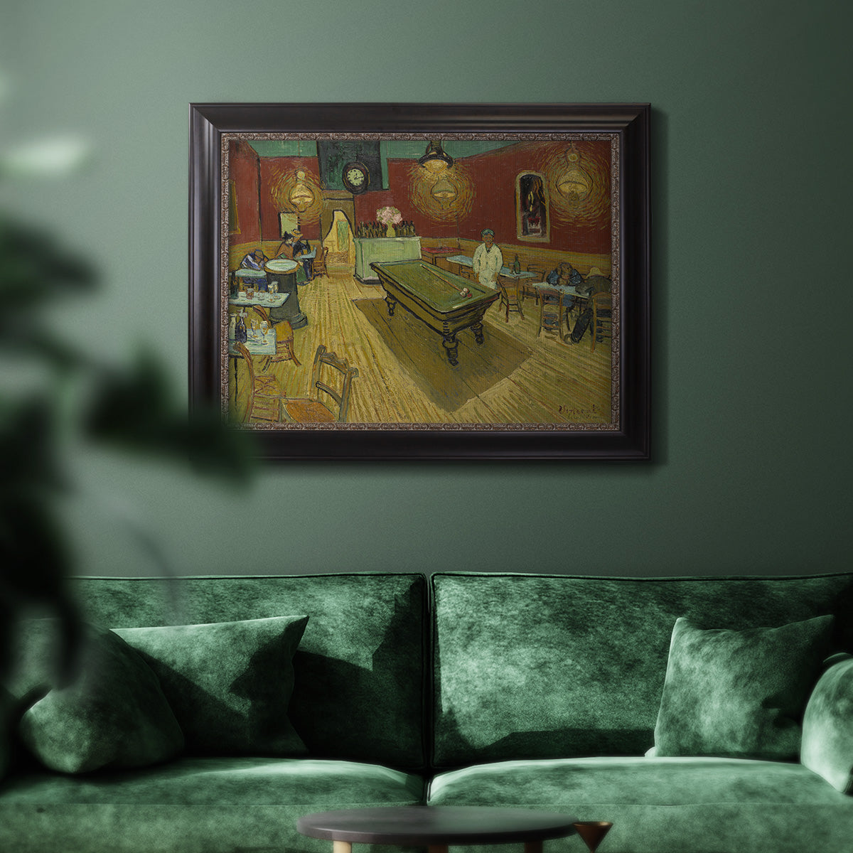 Impressionist interior of a night café by Vincent van Gogh in an ornate black frame with gilded inner detail displayed in a dark-toned interior setting.