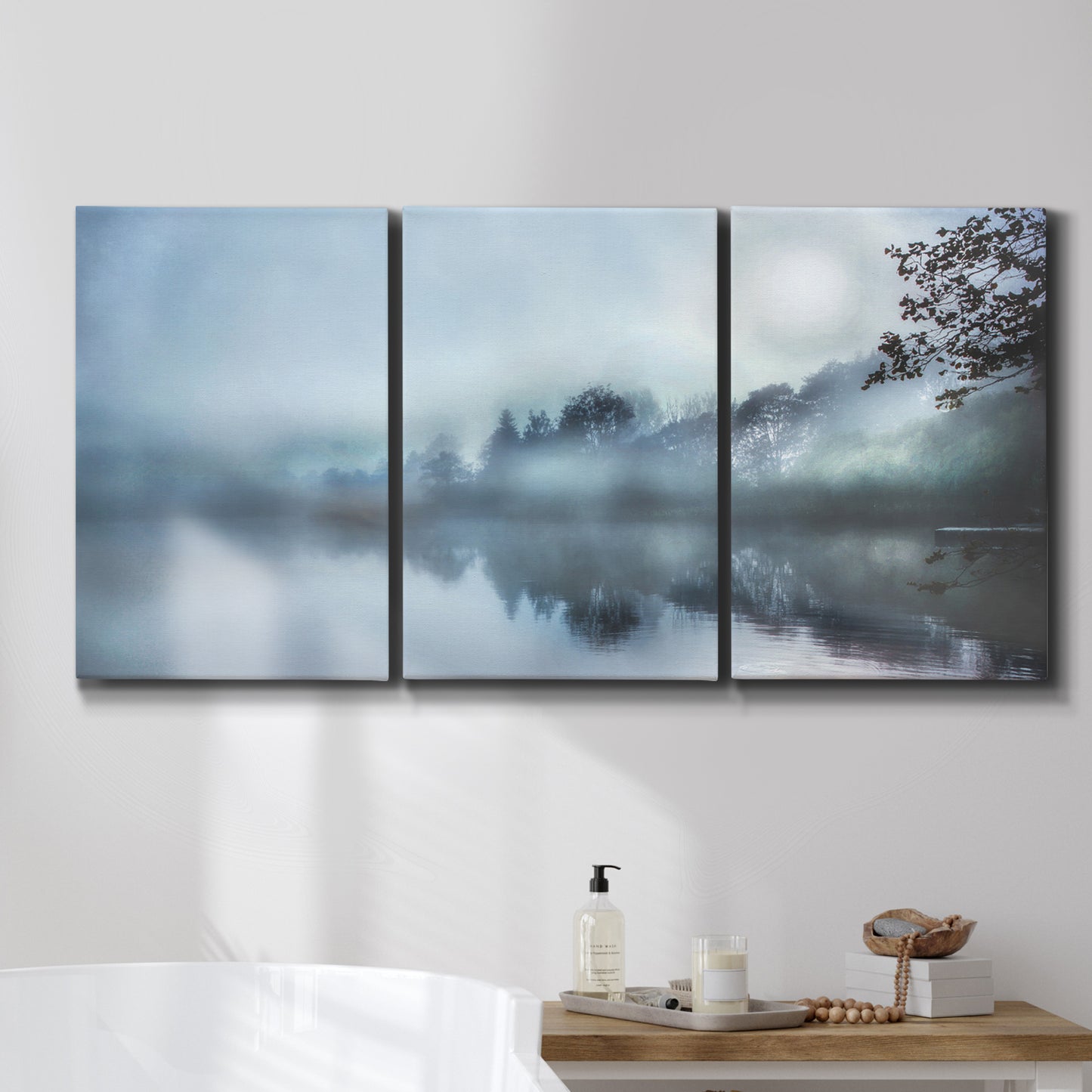 Three-panel canvas wall art featuring calm waters at sunrise photograph, displayed in a bathroom above a bathtub.