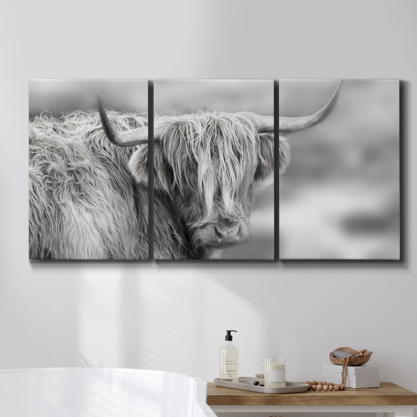 Three-panel canvas wall art featuring large highland cow portrait, displayed in a bathroom above a bathtub.