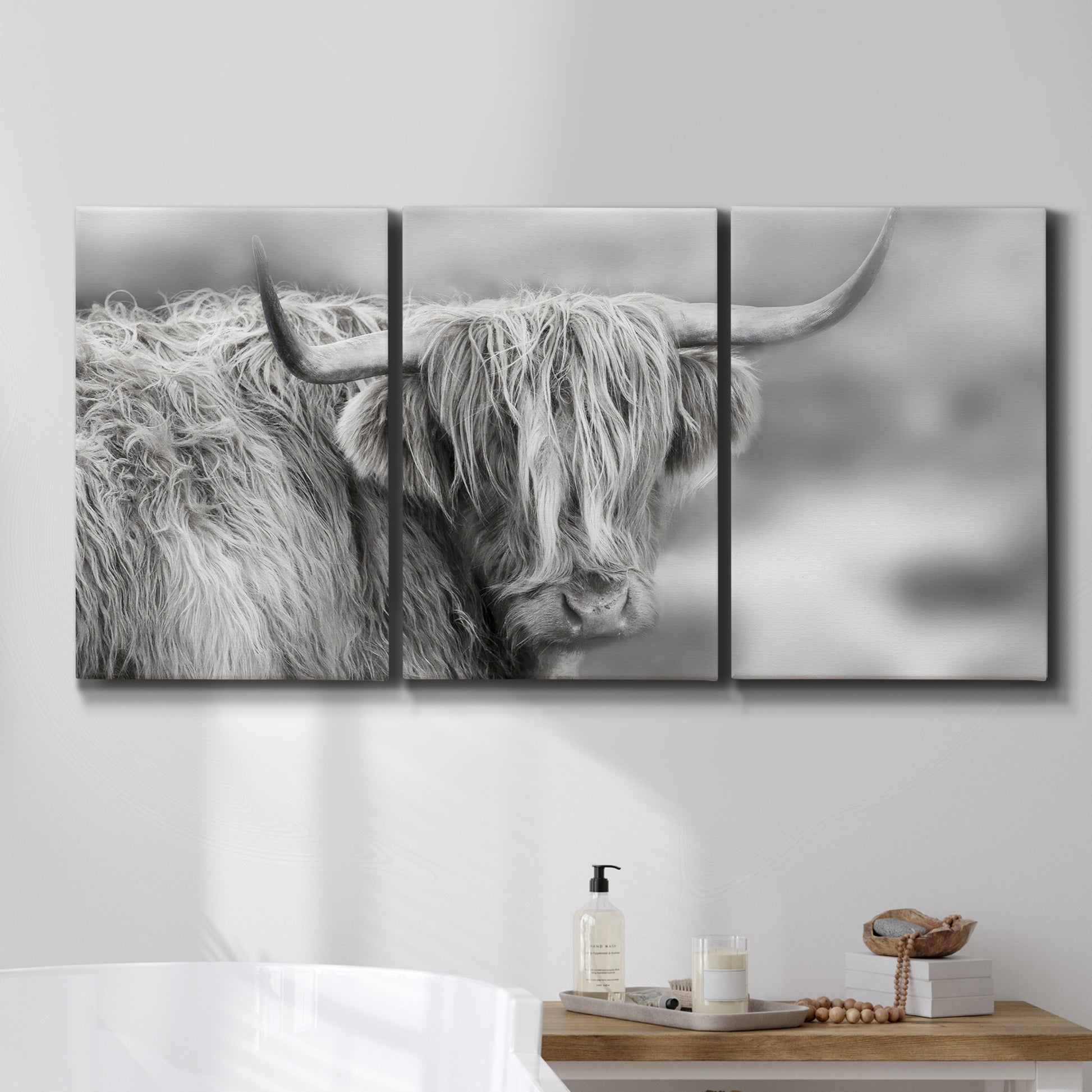 Three-panel canvas wall art featuring large highland cow portrait, displayed in a bathroom above a bathtub.