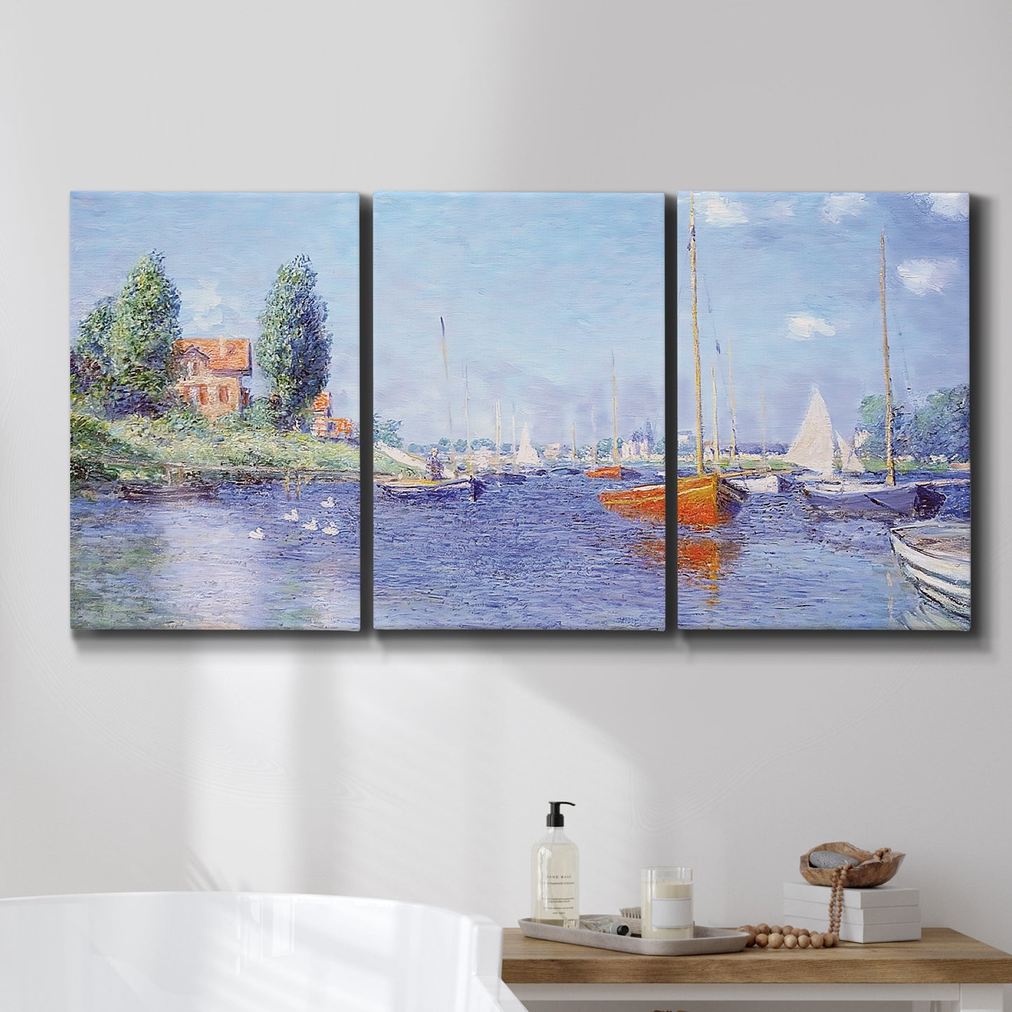 Three-panel canvas wall art featuring river flowing past riverside town, displayed in a bathroom above a bathtub.