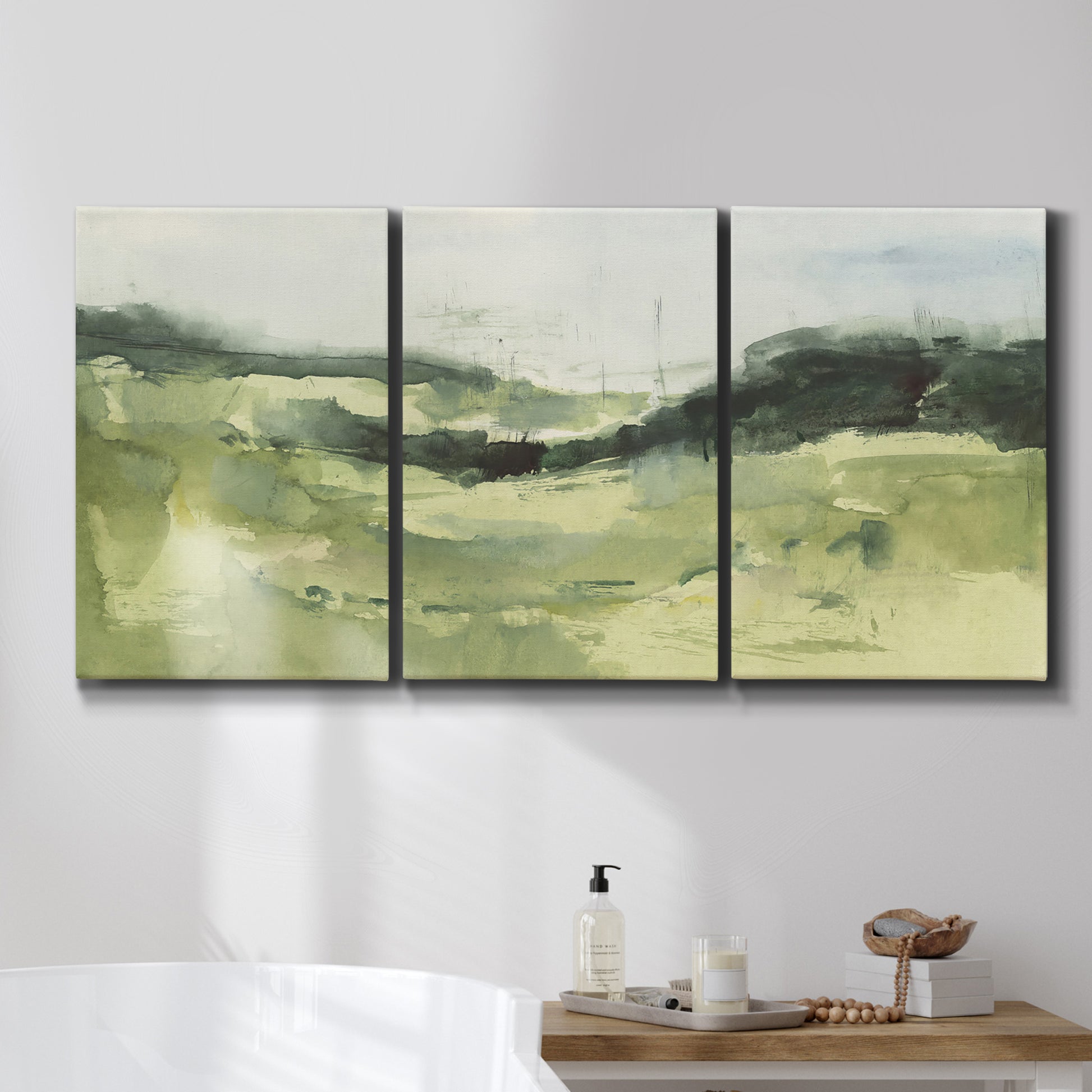 Three-panel canvas wall art featuring rolling hillside countryside landscape, displayed in a bathroom above a bathtub.
