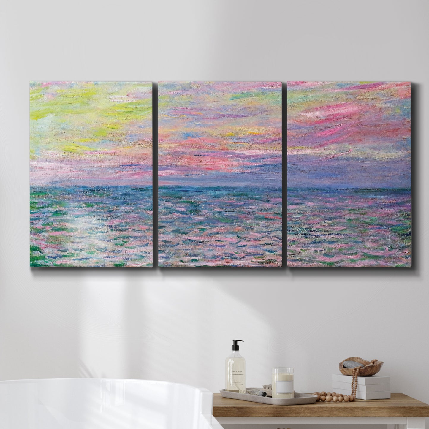 Three-panel canvas wall art featuring sunset reflections across calm sea, displayed in a bathroom above a bathtub.