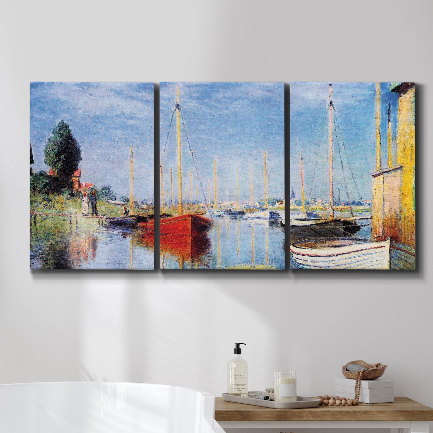 Three-panel canvas wall art featuring sailboats gathered along river, displayed in a bathroom above a bathtub.