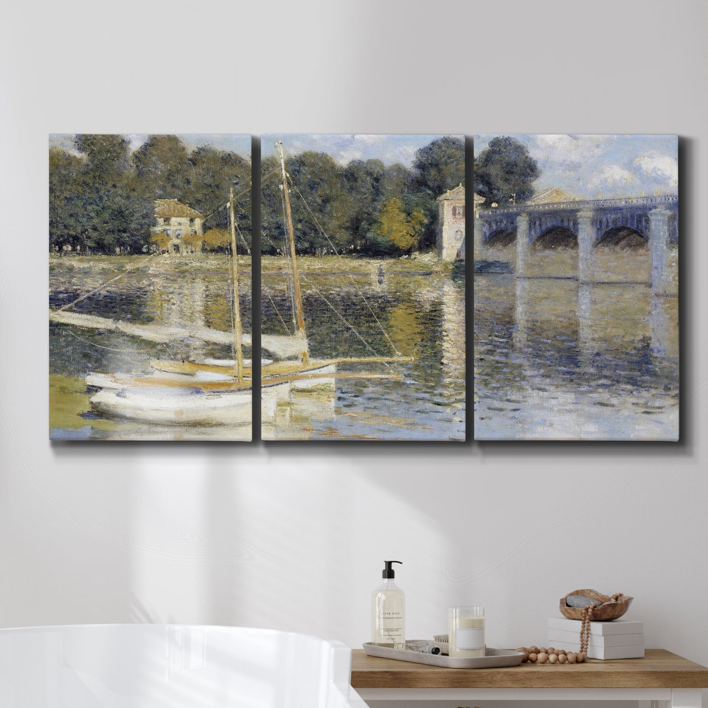 Three-panel canvas wall art featuring bridge crossing broad river, displayed in a bathroom above a bathtub.