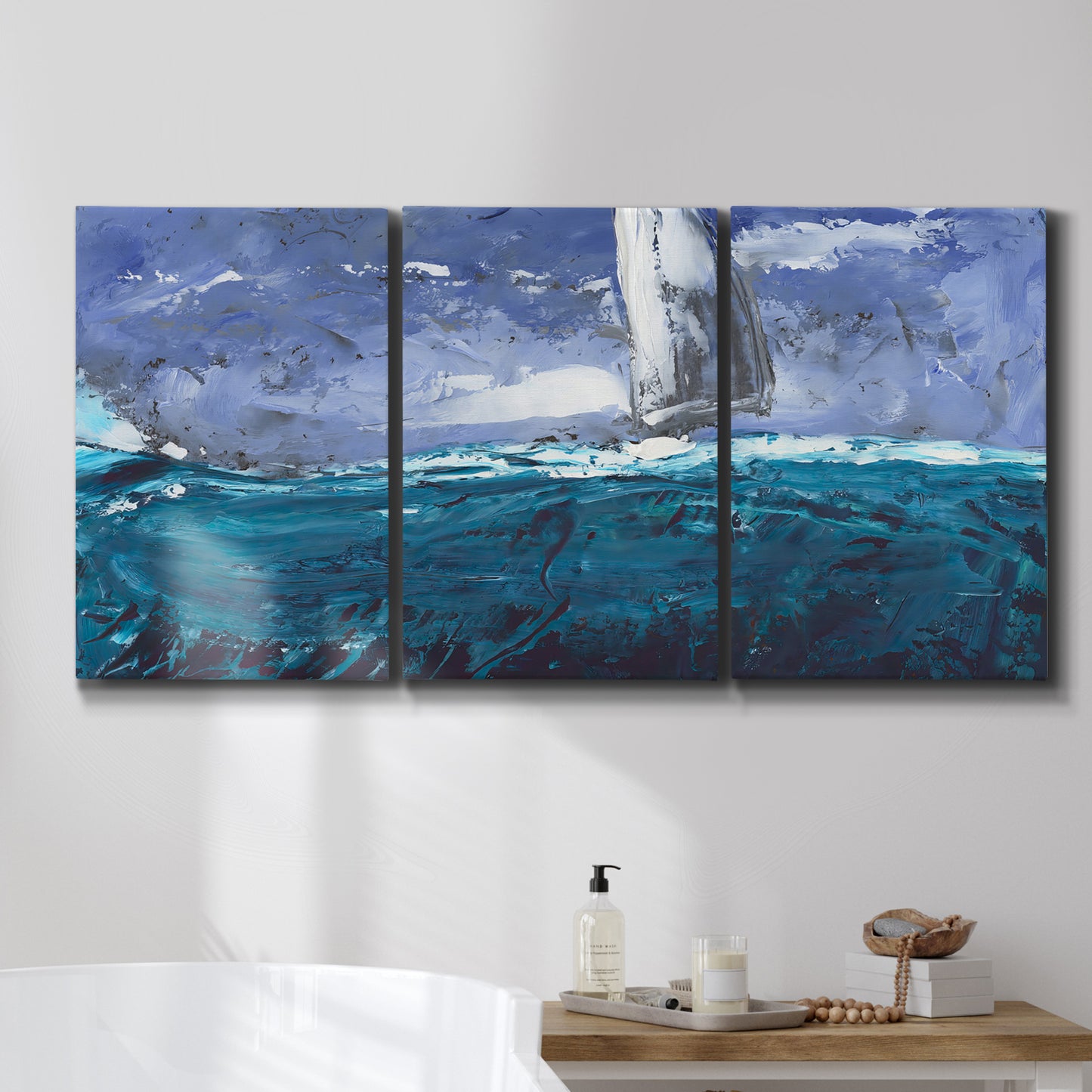Three-panel canvas wall art featuring sailboats moving across water, displayed in a bathroom above a bathtub.