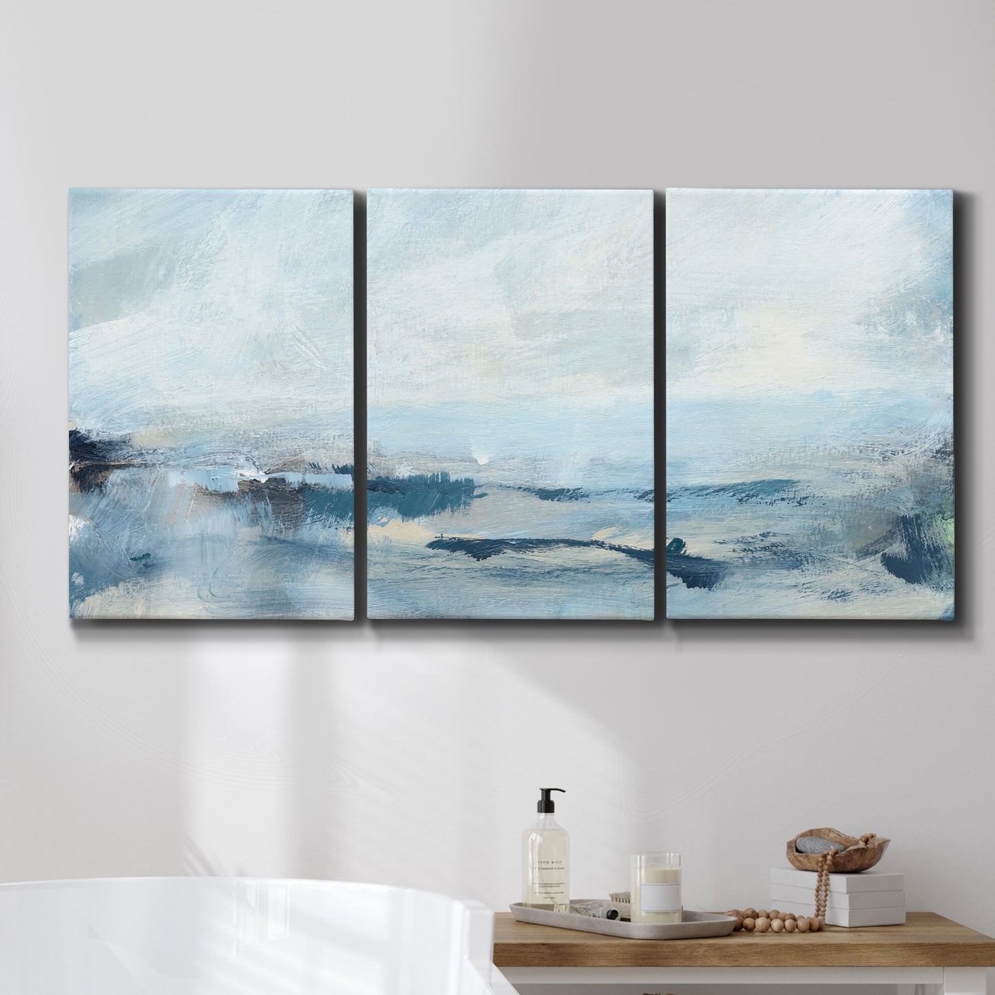 Three-panel canvas wall art featuring abstract sailboats on water, displayed in a bathroom above a bathtub.