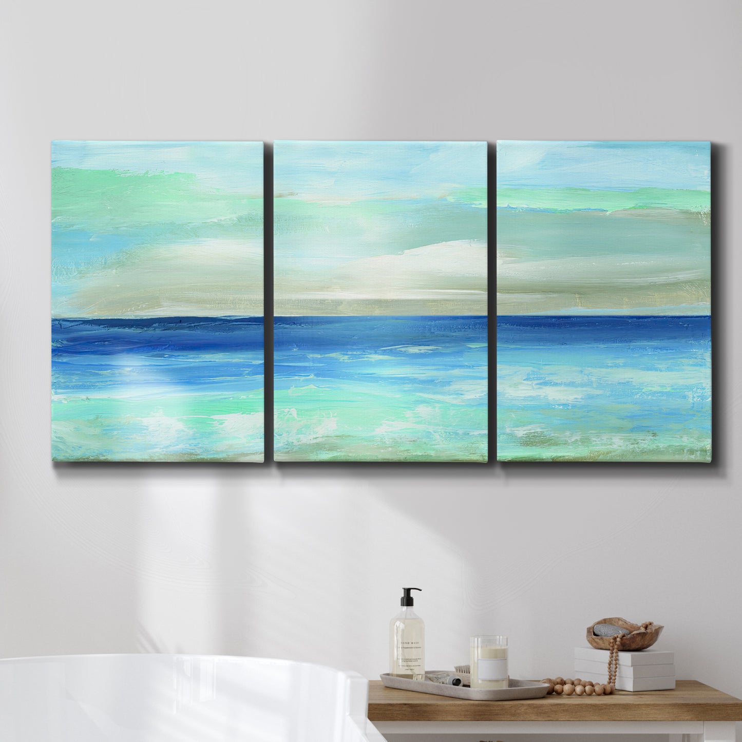Three-panel canvas wall art featuring vast open blue ocean horizon, displayed in a bathroom above a bathtub.