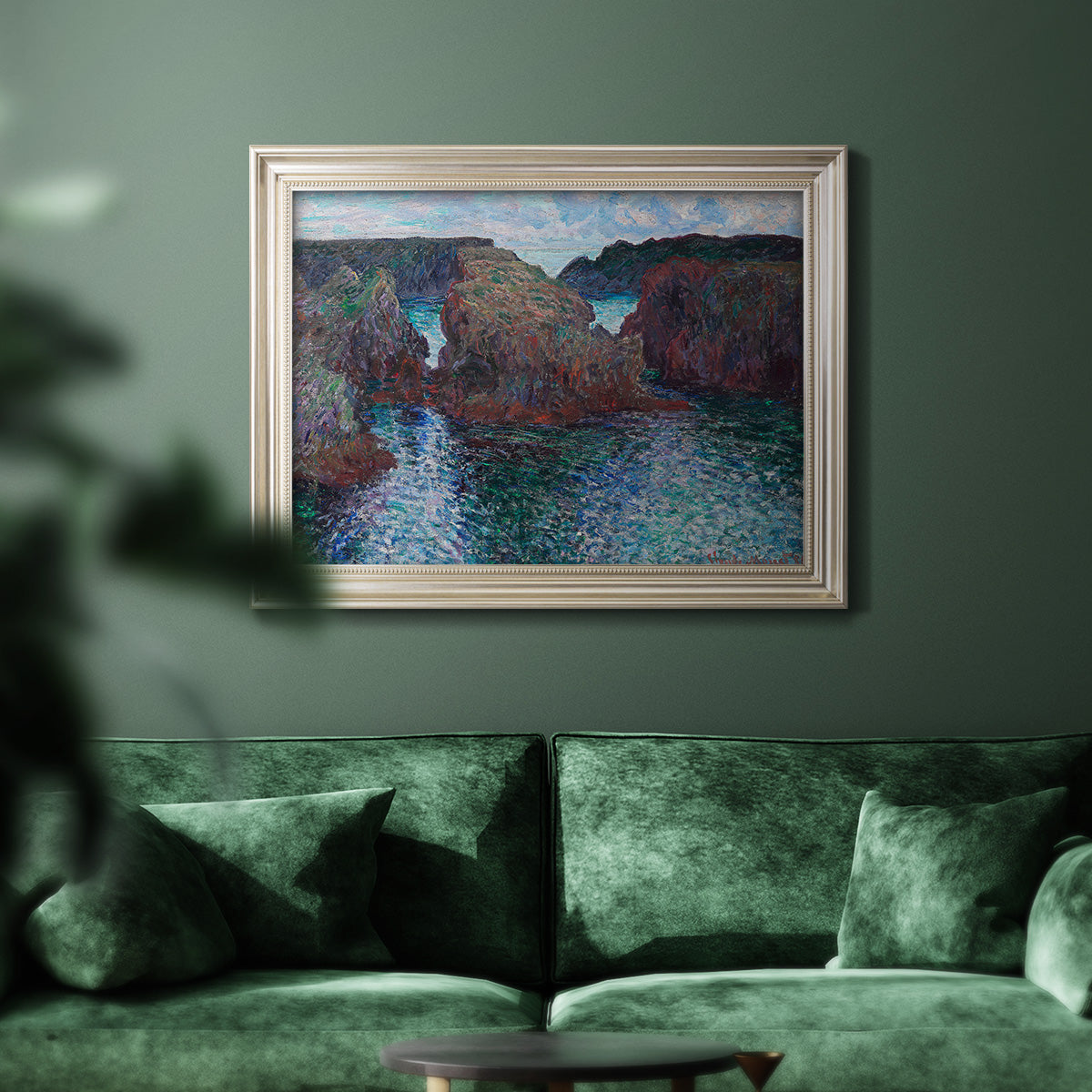Impressionist rocky seascape by Claude Monet in an ornate champagne frame displayed in a dark-toned interior setting.