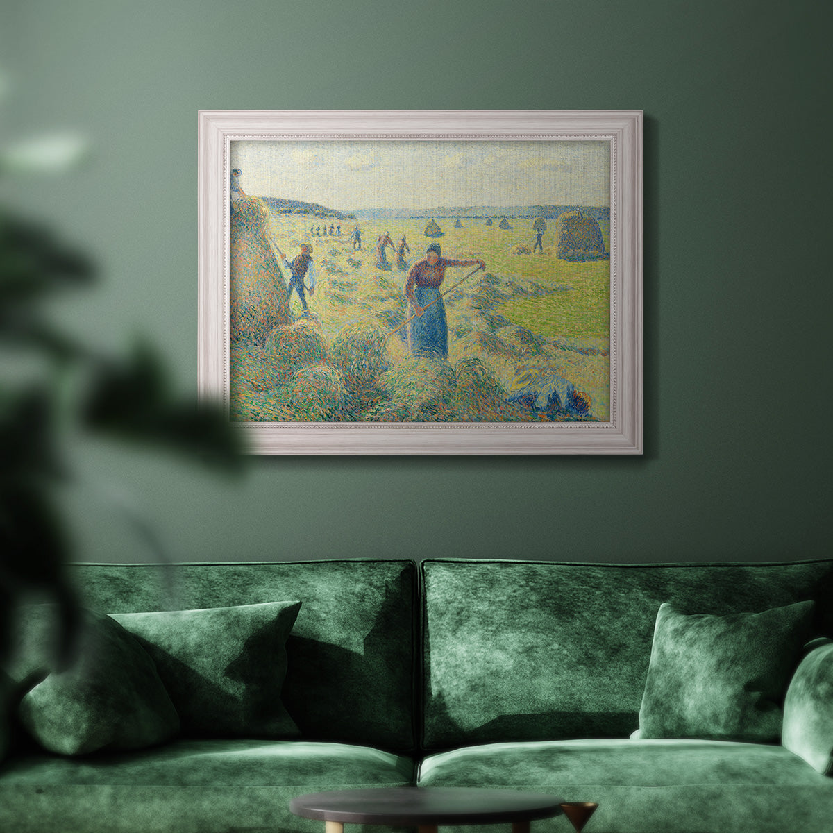 Impressionist rural hay harvest landscape by Camille Pissarro in an ornate weathered white frame displayed in a dark-toned interior setting.