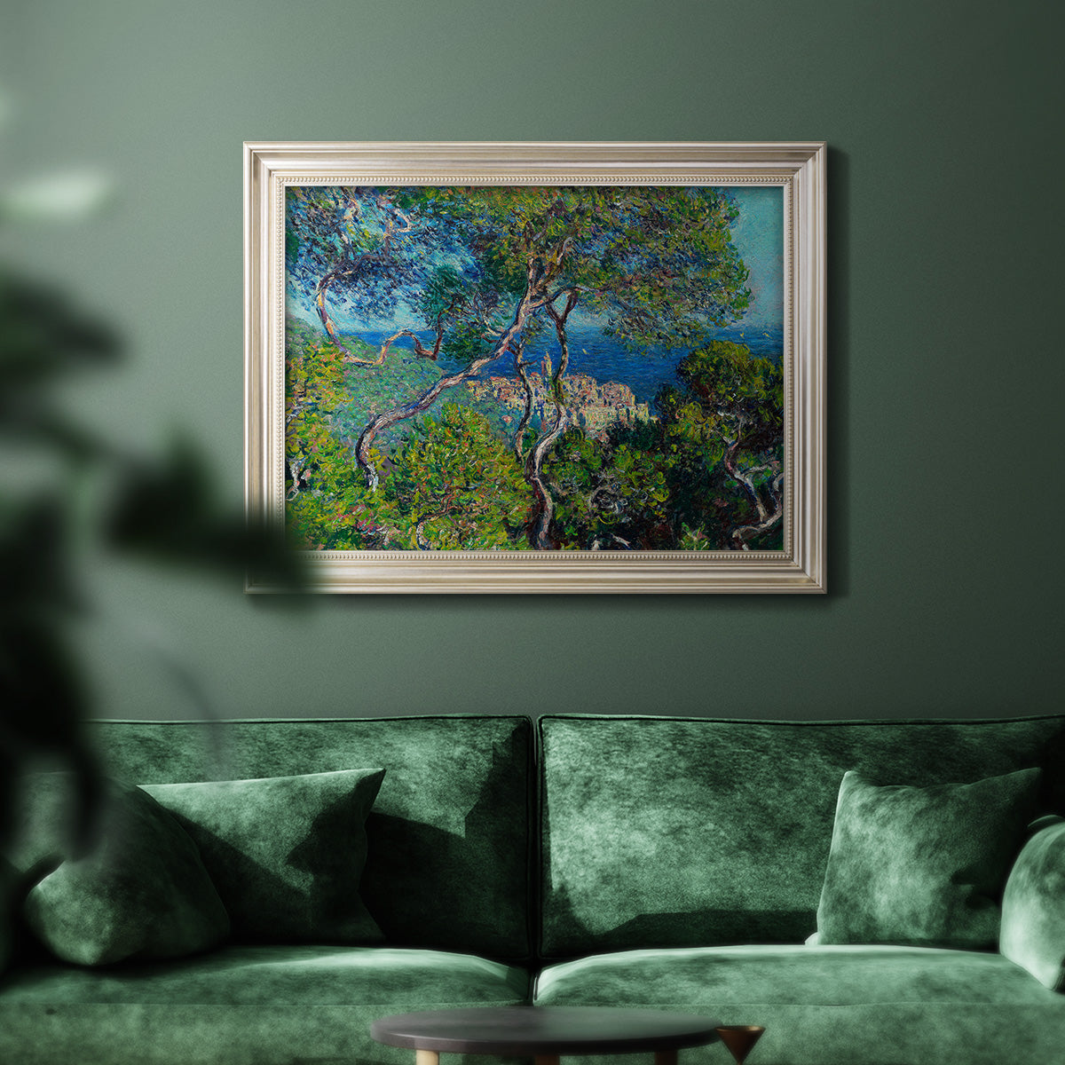 Impressionist Mediterranean coastal landscape by Claude Monet in an ornate champagne frame displayed in a dark-toned interior setting.