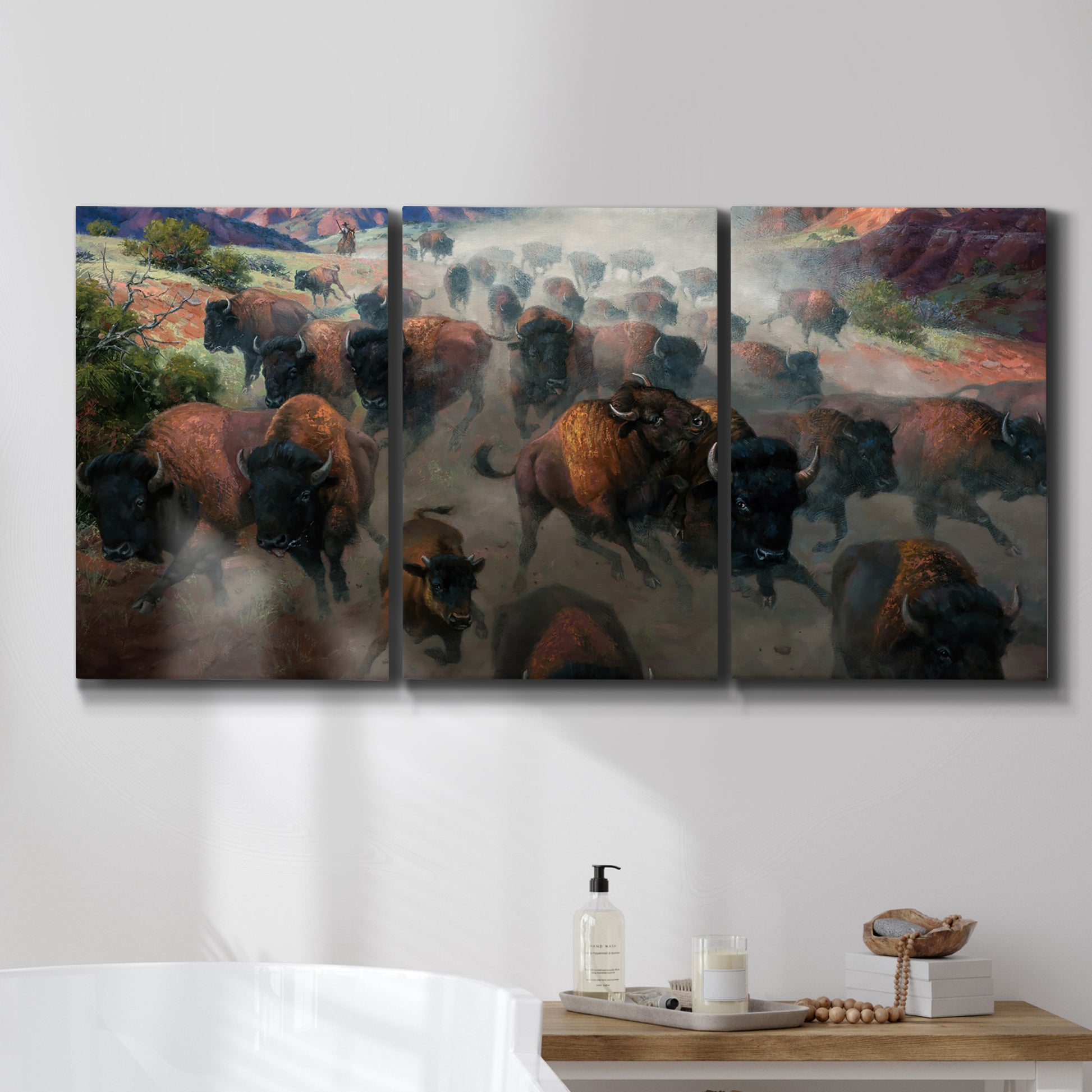 Three-panel canvas wall art featuring stormy canyon landscape with animals, displayed in a bathroom above a bathtub.