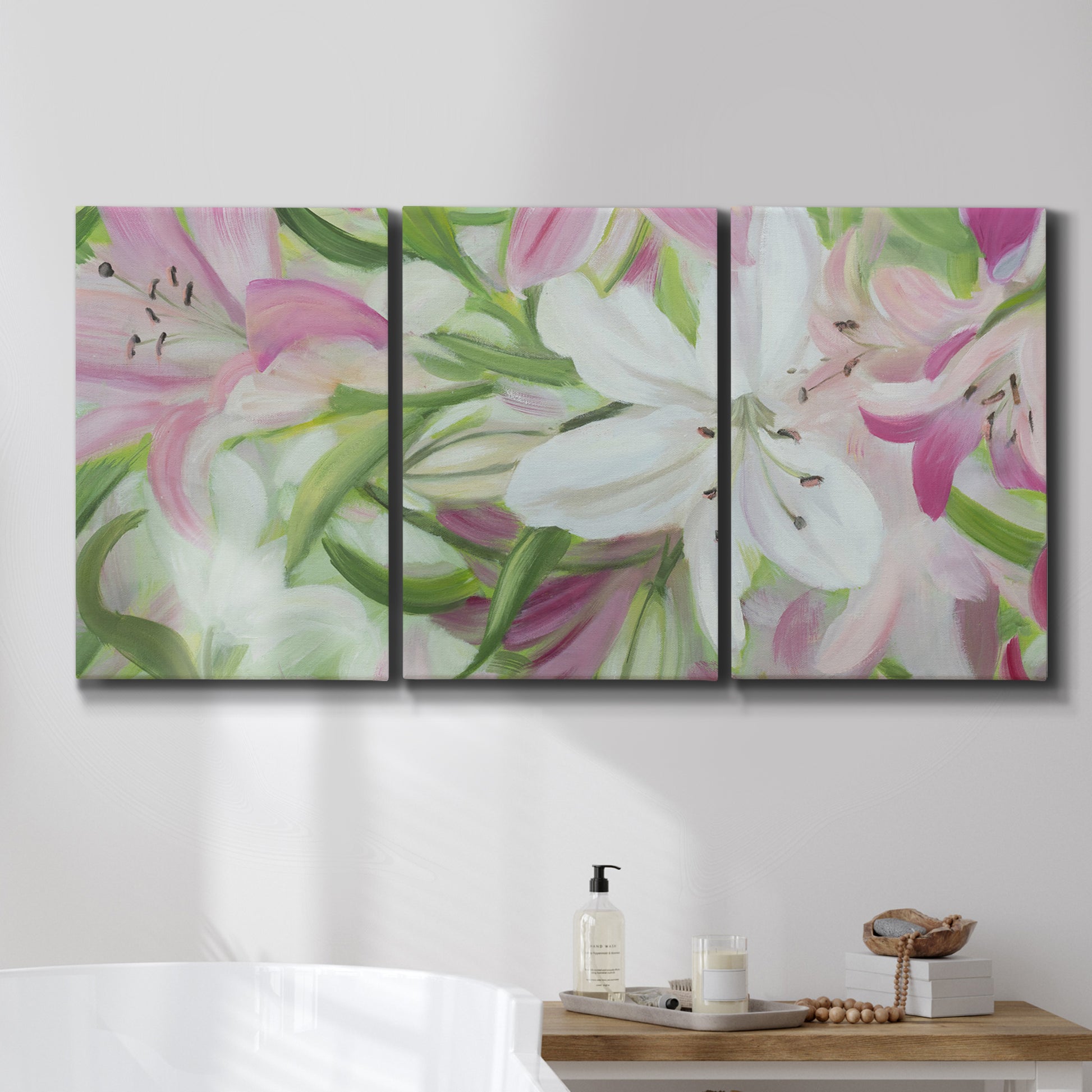 Three-panel canvas wall art featuring pink and white lilies botanical study, displayed in a bathroom above a bathtub.