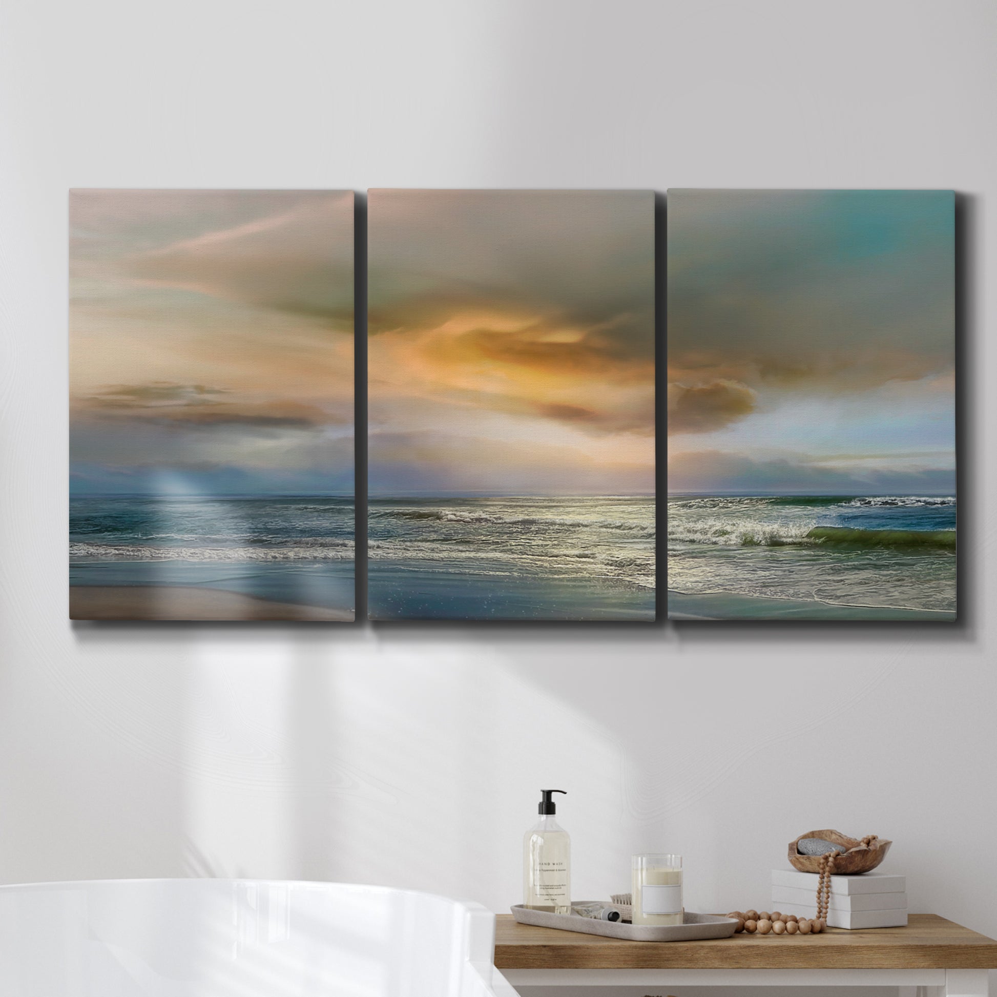 Three-panel canvas wall art featuring tranquil beach at sunset, displayed in a bathroom above a bathtub.
