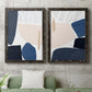 Set of two black barnwood framed canvas prints depicting a coordinated art pair of large navy cream and beige organic geometric shapes rendered as minimalist color-block abstracts above a sofa in a modern living room.