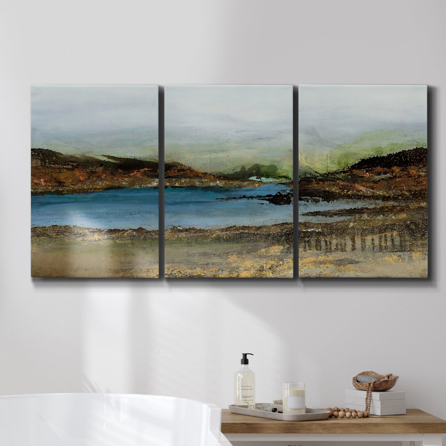 Three-panel canvas wall art featuring peaceful lakeside shoreline landscape, displayed in a bathroom above a bathtub.