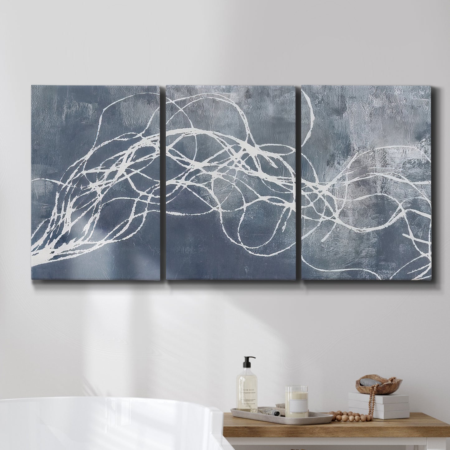 Three-panel canvas wall art featuring coastal shoreline at golden hour, displayed in a bathroom above a bathtub.